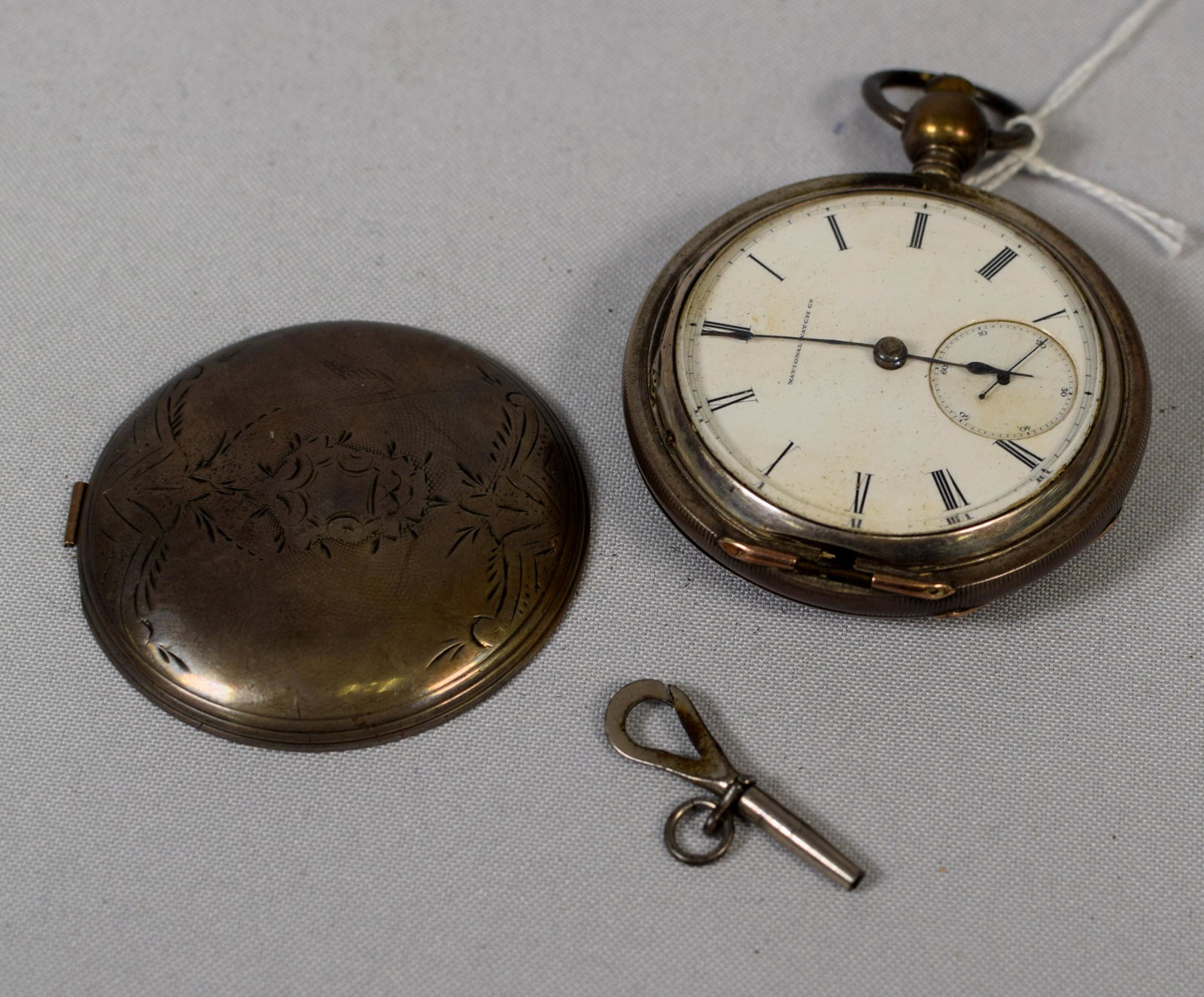 EARLY KEYWIND NATIONAL WATCH CO. POCKET WATCH: Coin silver hunter case. Keywind. Movement marked G. M. Wheeler Elgin #74,72 patent. Watch is working and as key. Front cover loose. Engraved silver case. watch 2 1/4 inches wide.