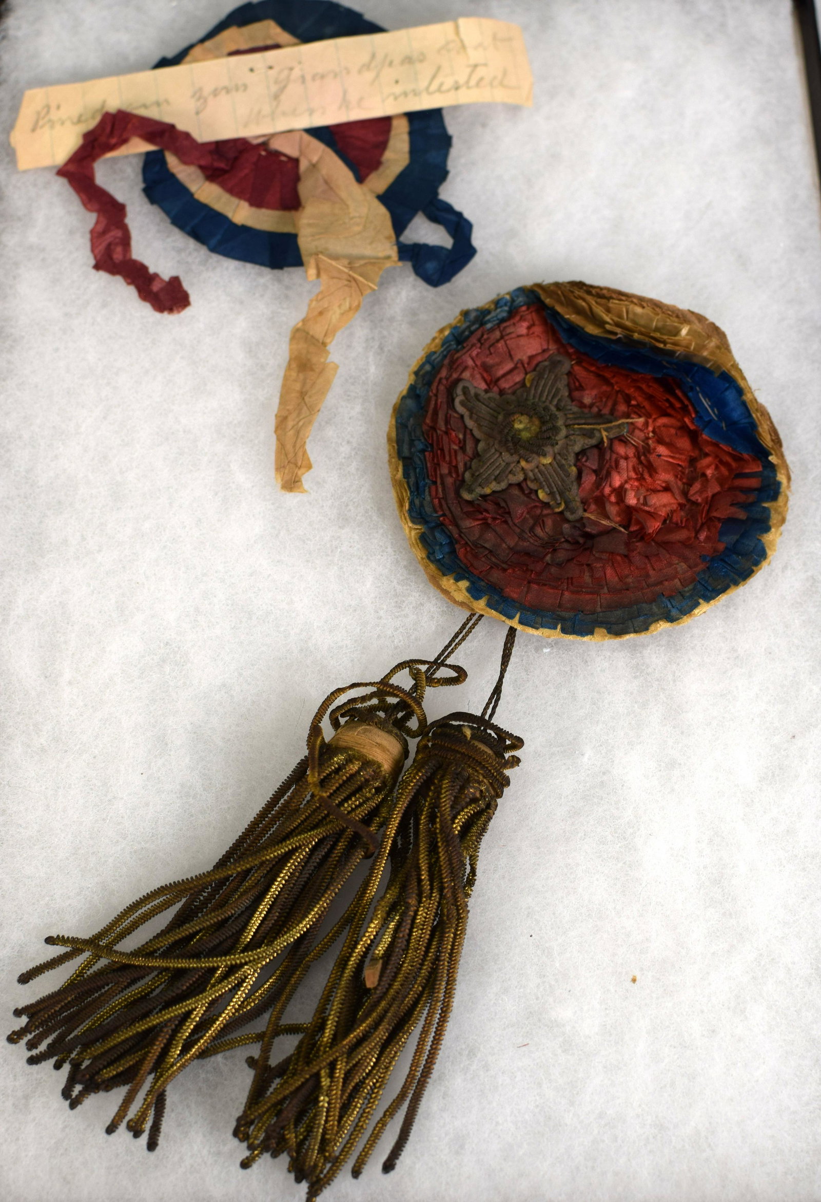 2 CONFEDERATE CIVIL WAR COCKADE UNIFORM ITEMS: Consists of two items. Hand-Crafted Sewn-Silk Cockade Confederate Secessionist Badge. One identified with note "pinned on Grandpa as he enlisted". The other much bolder with star withtassels. 3 1/2 in