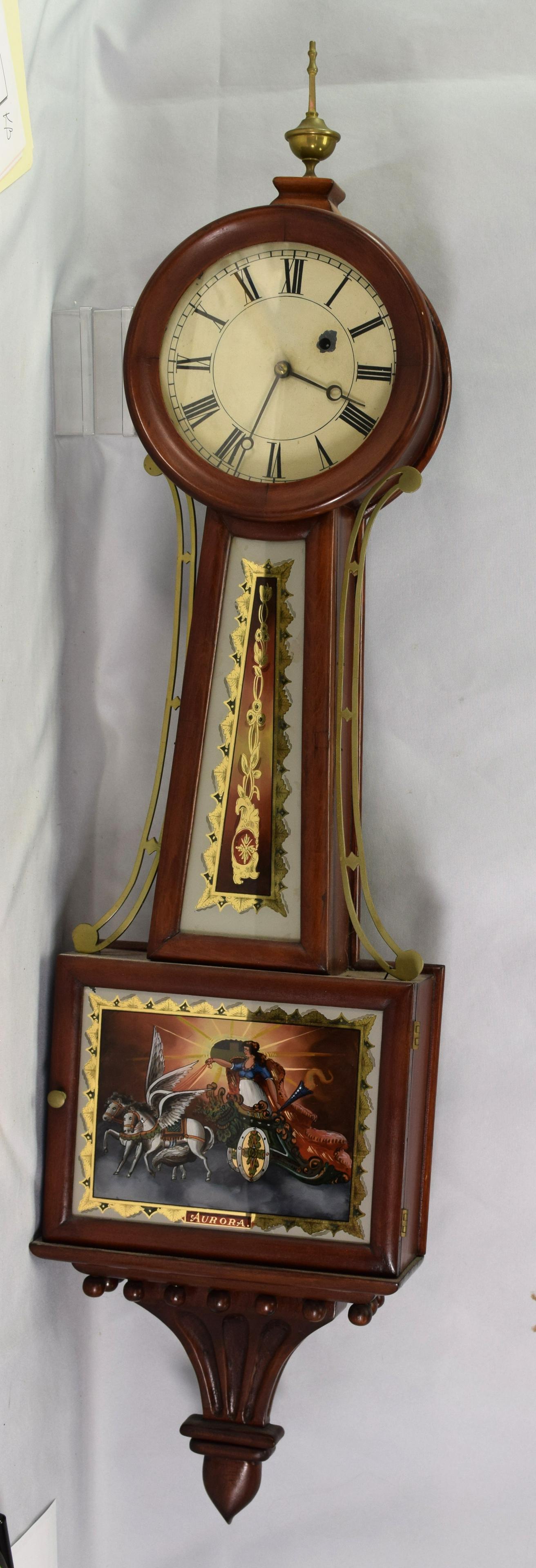 PERIOD BOSTON BANJO CLOCK: CA 1820. Boston banjo clock, mahogany and gilt. Painted metal 7 1/2 inch face with Roman Numerals. Minor loss to face around key hole. Reverse painted throat and panel depicting Aurora rising. Eight d