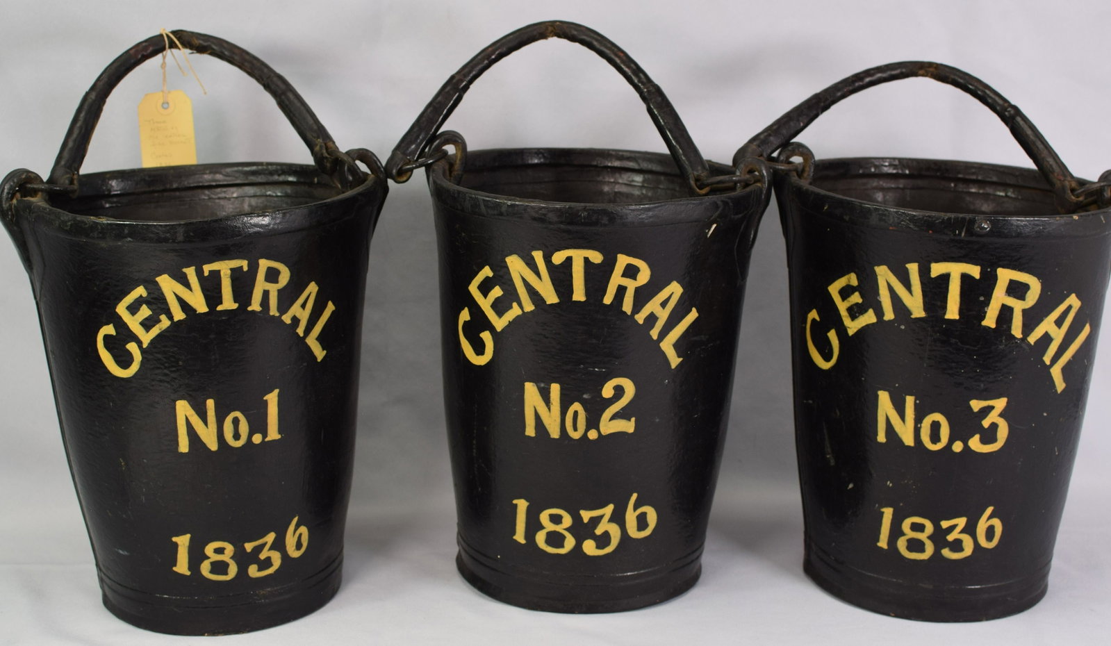 THREE MATCHING OLD AMERICAN LEATHER FIRE BUCKETS: Buckets marked Central 1836 NUMBERS 1, 2, and 3. Early auction tag of W. Torrey Little Inc. Auction Barn 575 Summer St. Marshfield, Mass. #51 Fox Est. Original handles. 12 inches tall. Goodcondition.