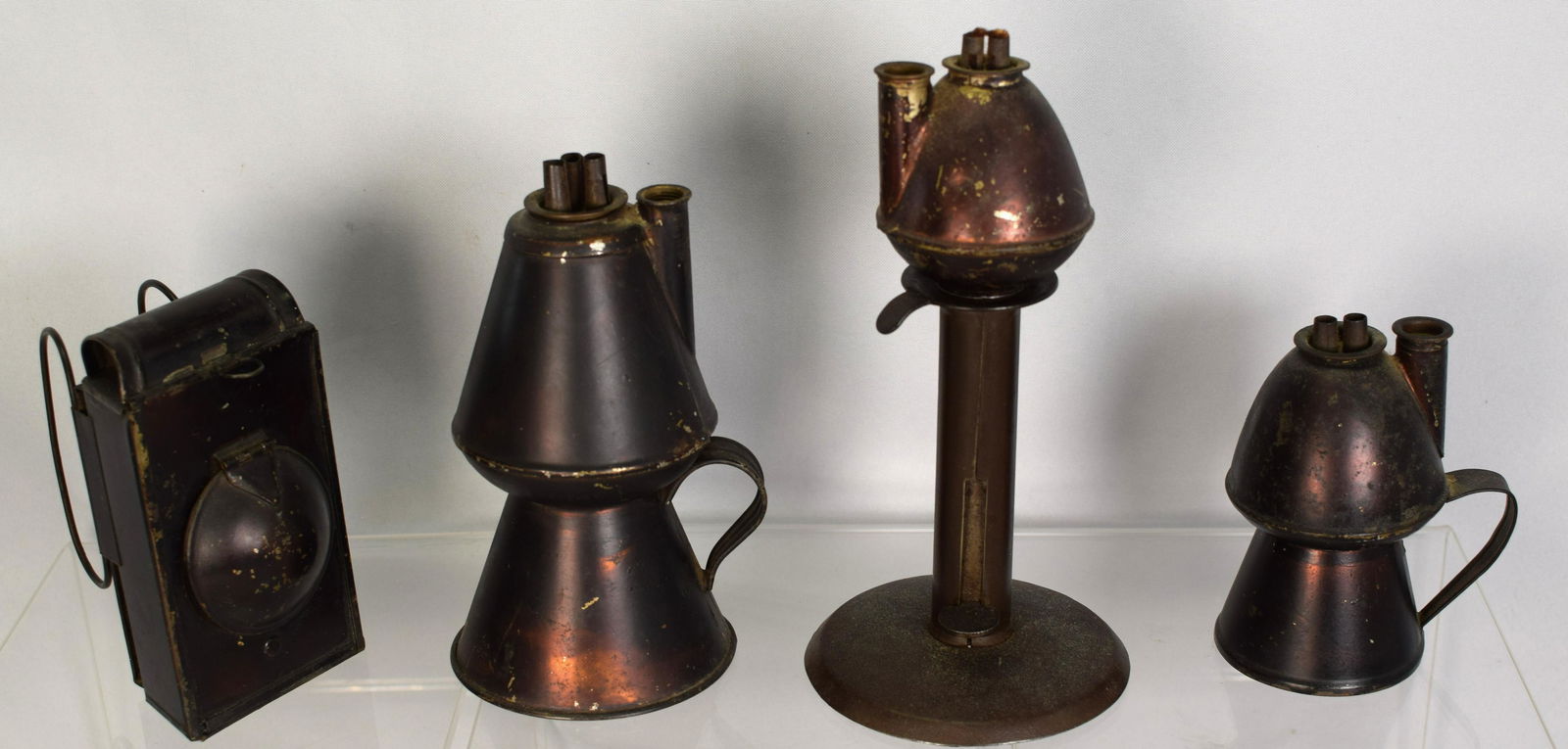 (0N-4) SHEET IRON JAPANNED PETTICOAT OIL LAMPS: Ca mid 19th century. American whale oil lamps. Lot of four. Each with Japanned finish. Consists of 1) with strap handle, double burners. 4 1/2 inches tall. Good condition. 2) is a peg whale oil lamp i