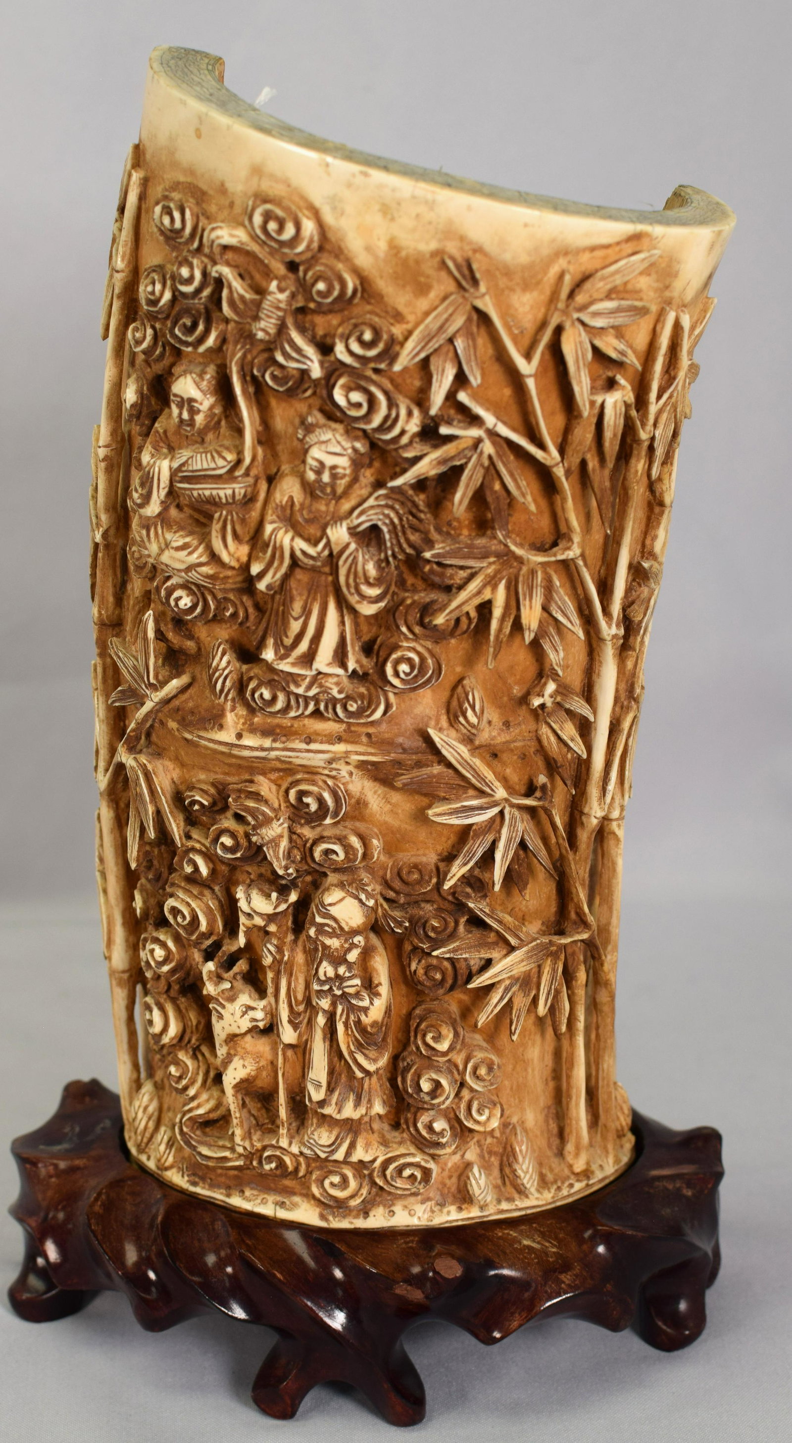 CHINESE ORNATELY CARVED TUSK SECTION: On carved rosewood fitted stand. Ca late 18th/early 19th century. Very detailed relief carved with figures, bamboo and animals. One with a bat flying out of a box and one with a snake and dear. Woman 