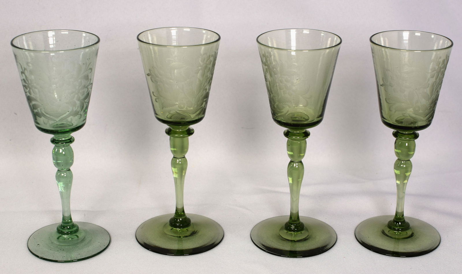 4 STEUBEN GREEN ETCHED GLASS CORDIALS BUBBLES: 4 Beautiful green hand blown cordials by Steuben with large etched flower motif. Have natural bubbles. All 4 signed on bottom. Nice glasses.