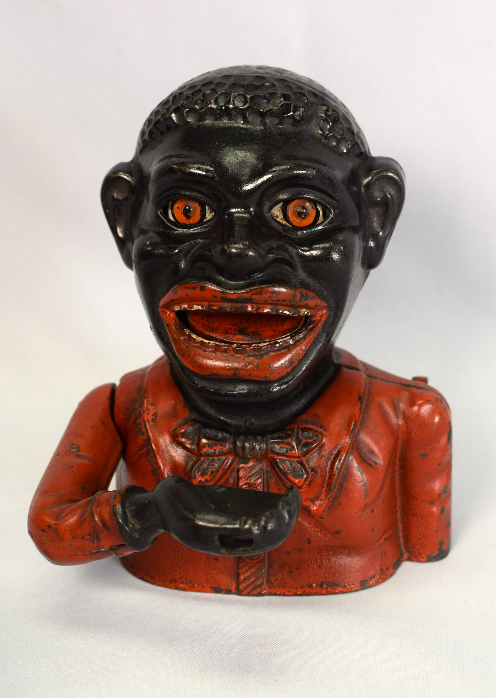BLACK AMERICANA JOLLY CAST-IRON MECHANICAL BANK: Marked "JOLLY NIGGER BANK" to reverse and "MADE IN ENGLAND" to underside of base. Working condition with original paint. John Harper & Co., England. Late 19th/early 20th century. 6 1/2" x, 5 1/4inches