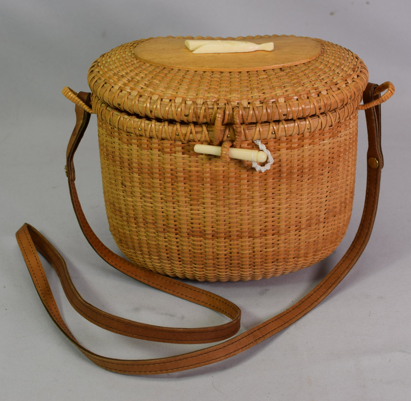 NANTUCKET BASKET PURSE BY GEO. W.: Wonderfully crafted Nantucket basket purse with whale bone whale on the top and lid lock. Leather strap (approx 44 in.) Measures 9 x 6 x 8 in. Excellent condition.