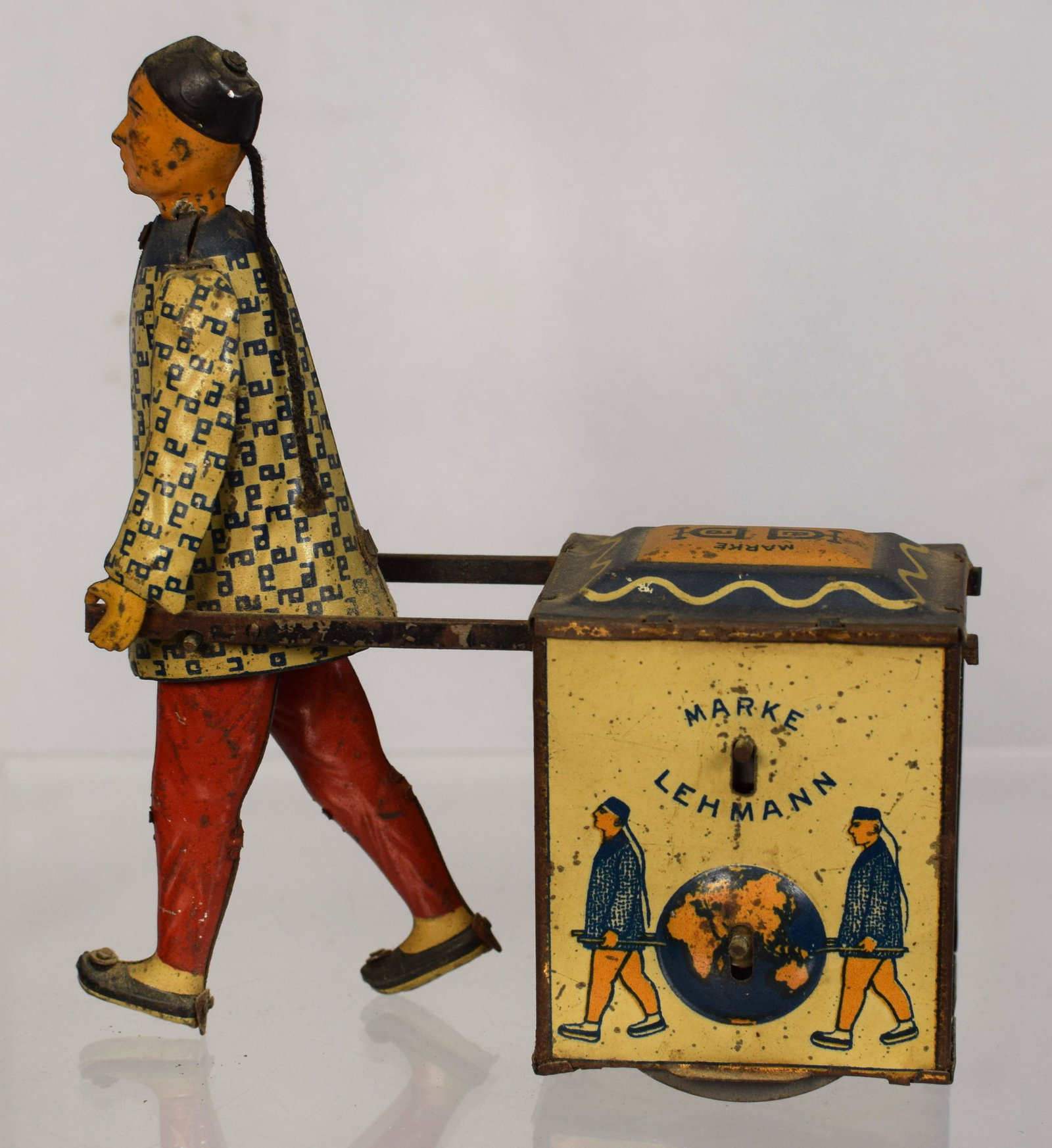 MARKE LEHMANN TIN LITHO NU-NU WIND UP TOY: Lehmann tin litho Nu-Nu toy depicting a Chinese porter in blue and white clock and red pants pulling a cart, signed and picture of 2 figures and globe. Base with patent dates 1903, 1907 and1913. Measu