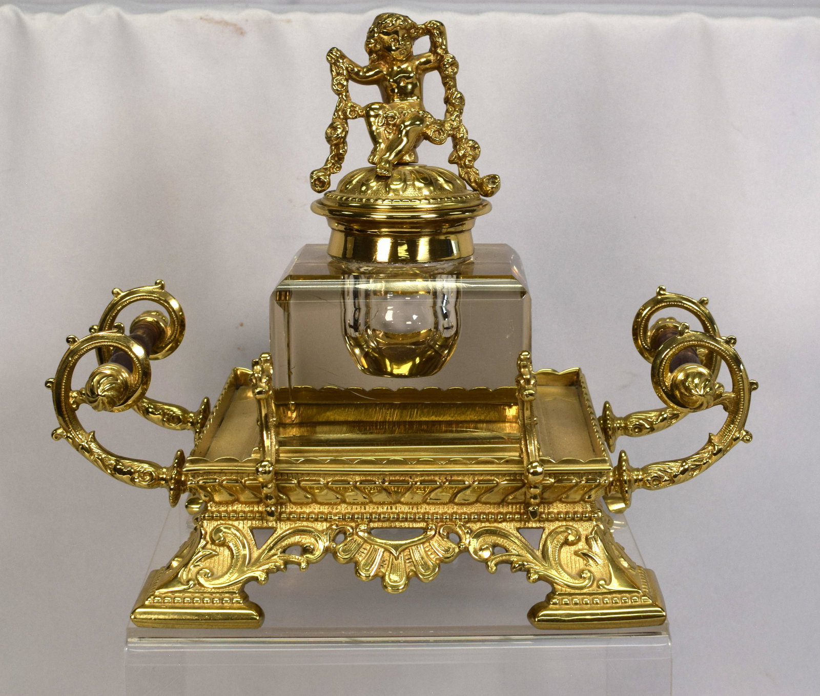 VERY ORNATE GILDED BRONZE & CUT GLASS INKWELL: Ca 19th/20th century. Gilded bronze footed base with side turned wooden handles. Square cut glass inkwell with hinged cherub finial Approx 11 inches x 8 inches x 9 inches tall. Only markings number853