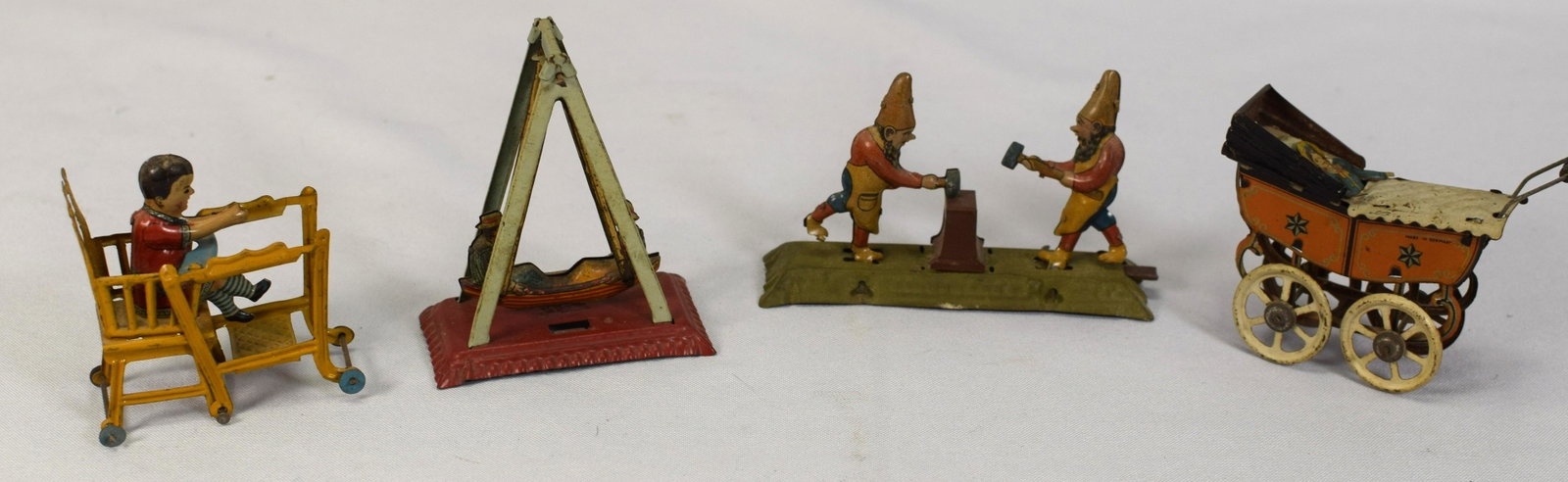 (on-4) EARLY TIN LITHO PENNY TOYS: Consists of 1) Tin Litho Gnomes blacksmiths penny toy. Push-level works. Paint original patina in good condition. 4 inches long. 2) German tin litho stroller penny toy. 3 1/4 inches. Some wear topaint