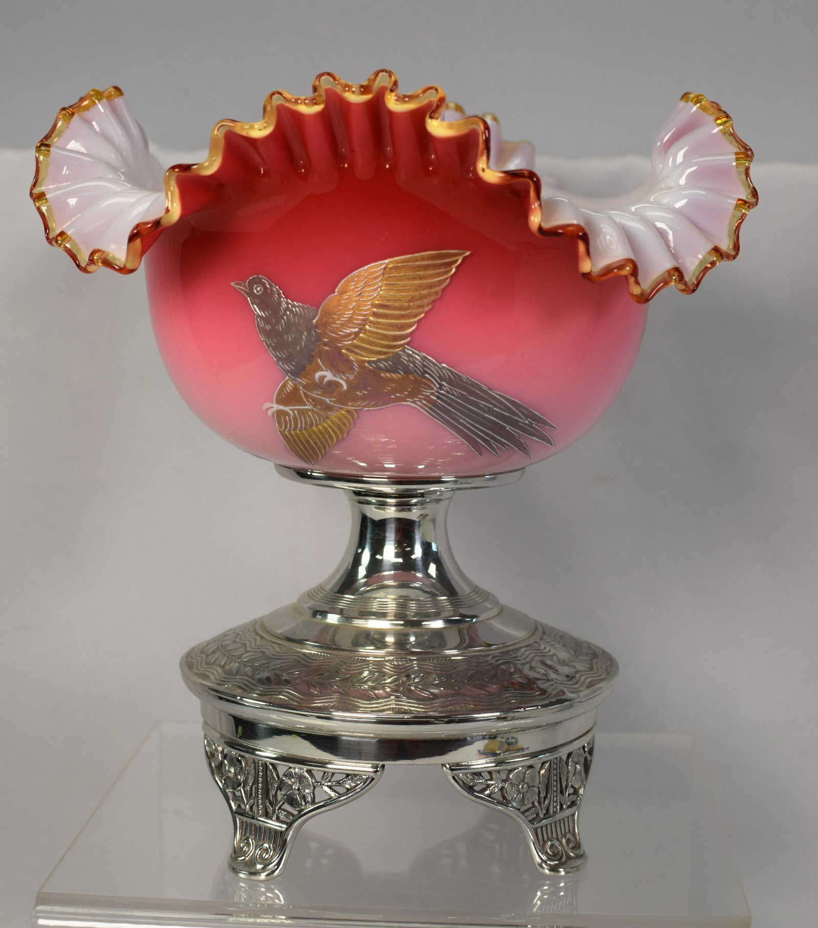 19TH SILVERPLATE MT WASHINGTON BRIDES BASKET: Ca 19th. Pairpoint signed silverplate and cased Mt. Washington glossy burmese glass brides basket. Bowl ruffle edge with enamel bird in flight and flower hand painted decoration. 9 inches tall x 91/2 