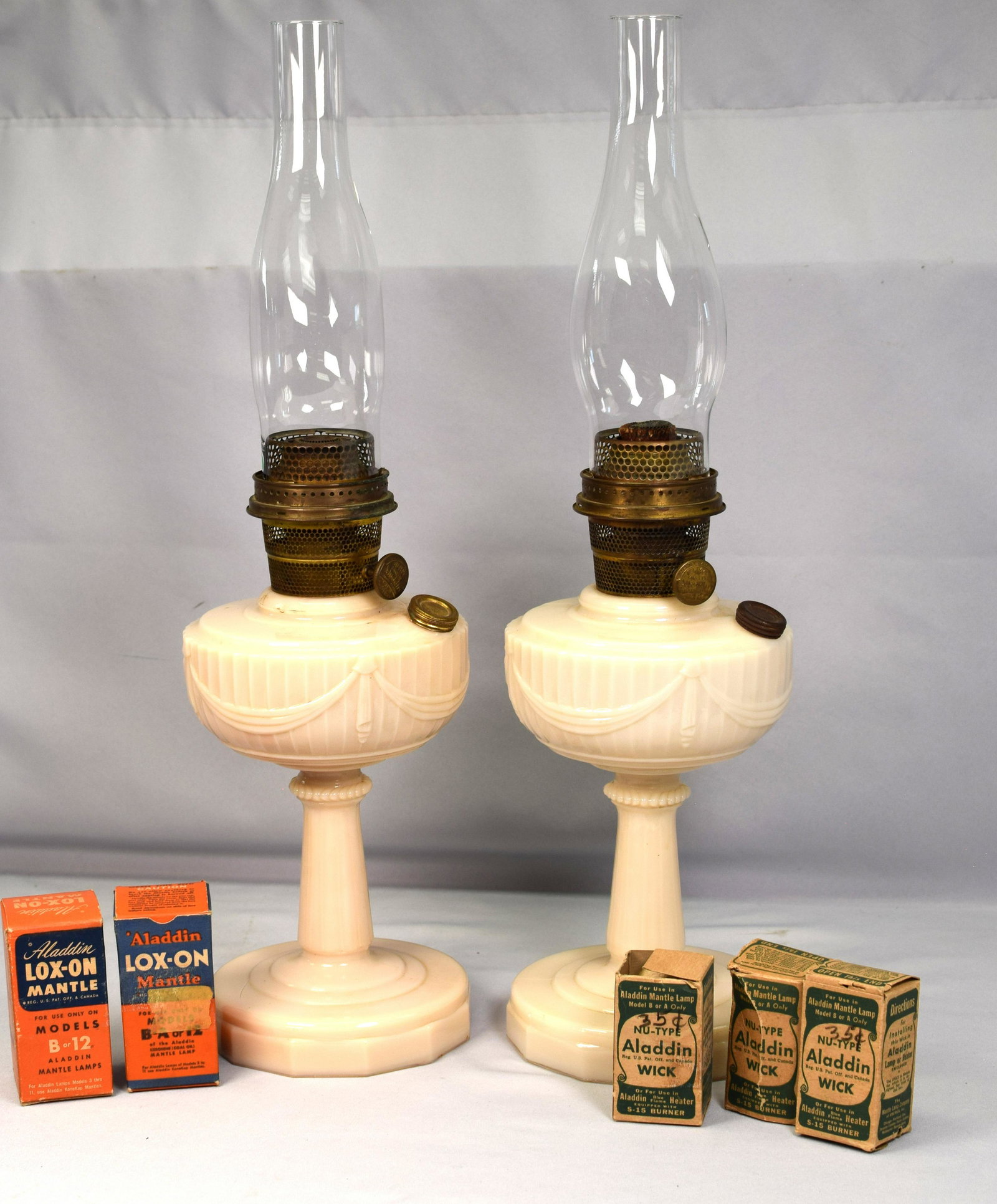 (on-2) ALADDIN LINCOLN DRAPE ALACITE OIL LAMPS: Aladdin pre-war Lincoln drape kerosene lamps. Both in good condition. Lot comes with 5 boxed wicks. Two chimneys. Lamps 13 1/2 inches tall without chimney x 6 inches diameter. Shipping 9 pounds.