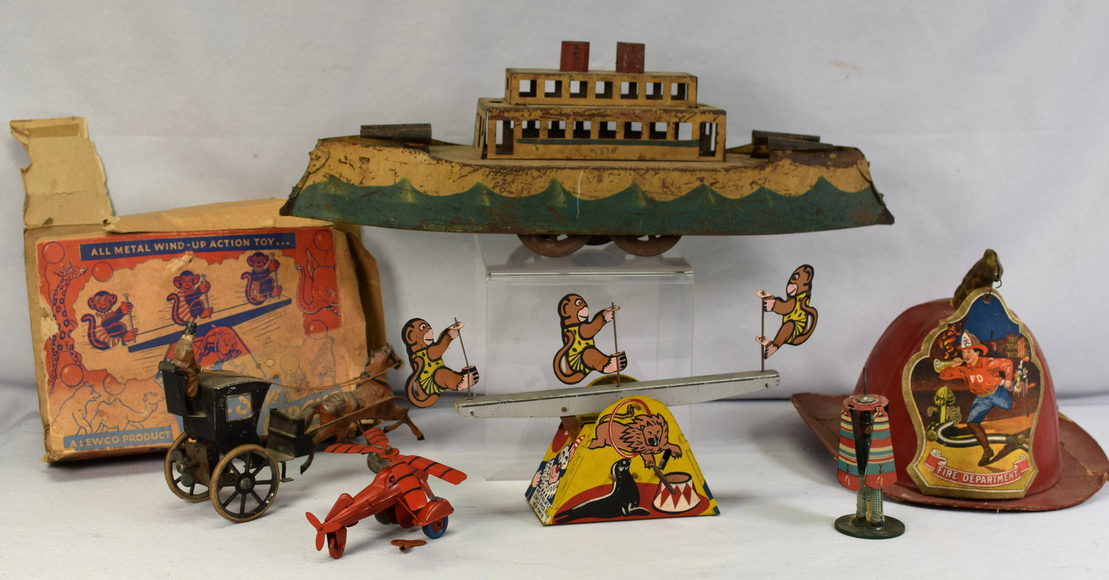 SET OF VINTAGE TOYS: Set includes; 1.) Wind up see-saw circus made by Lewco products, functional. 2.) Red tin helicopter 3.) Dayton Hill climber battle ship, worn and has paint loss. 4.) Toy British Hansome cab, slightpai