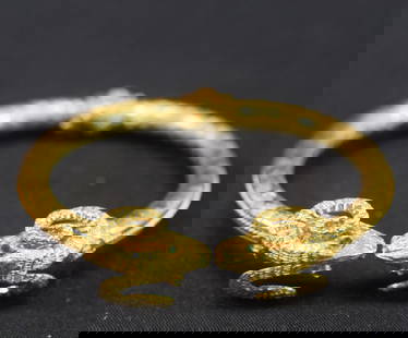18K MYTHICAL RAM HORNED SNAKE BANGLE BRACELET: Marked 750 and tested 18k. Hinged bangle bracelet. Mythical ram horned bracelet with emerald eyes. 18.1 DWT. Good condition. Whites Auctions does not grade coins. Whites will not accept credit cards o