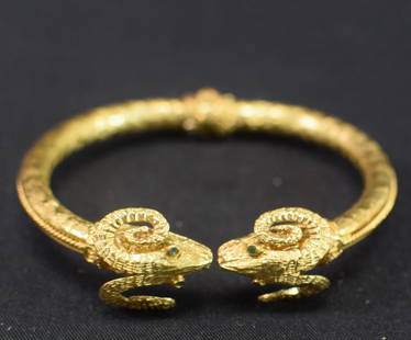 18K MYTHICAL RAM HORNED SNAKE BANGLE BRACELET: Marked 750 and tested 18k. Hinged bangle bracelet. Mythical ram horned bracelet with emerald eyes. 18.1 DWT. Good condition. Whites Auctions does not grade coins. Whites will not accept credit