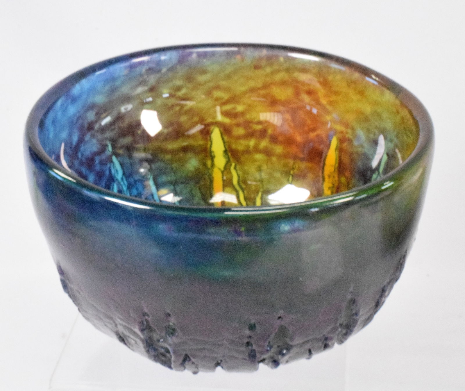 KOSTA BODA GORAN WARFF SCANDINAVIAN ART GLASS BOWL: Ca 1960's. Heavy deep molten form deep bowl with bold bleeding colors of blues, greens, golds and purple. Textured surface exterior, smooth interior. Measures 8 inches in diameter x 5 1/8inches tall.