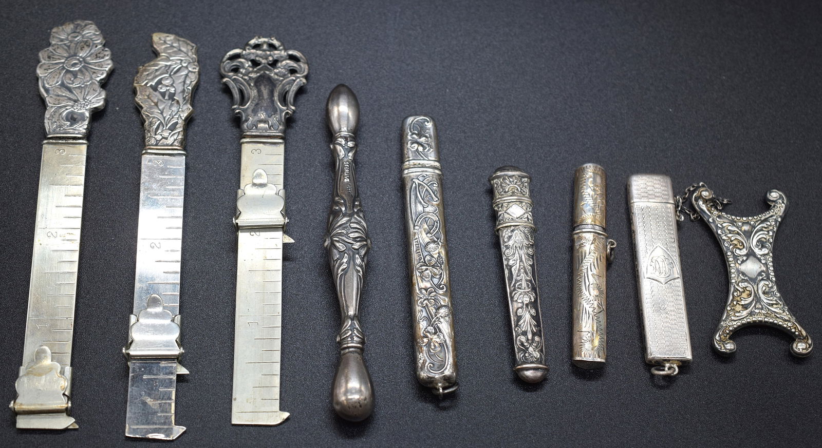 VICTORIAN STERLING SEWING MEASURES & NEEDLE CASES: Nine pieces. Three sterling silver sliding rules with repousee handles, 3 sterling needle cases, 1 sterling pencil case, silver repousee thread "spoon", and unknown tool. Approximately 7 grams,approxi