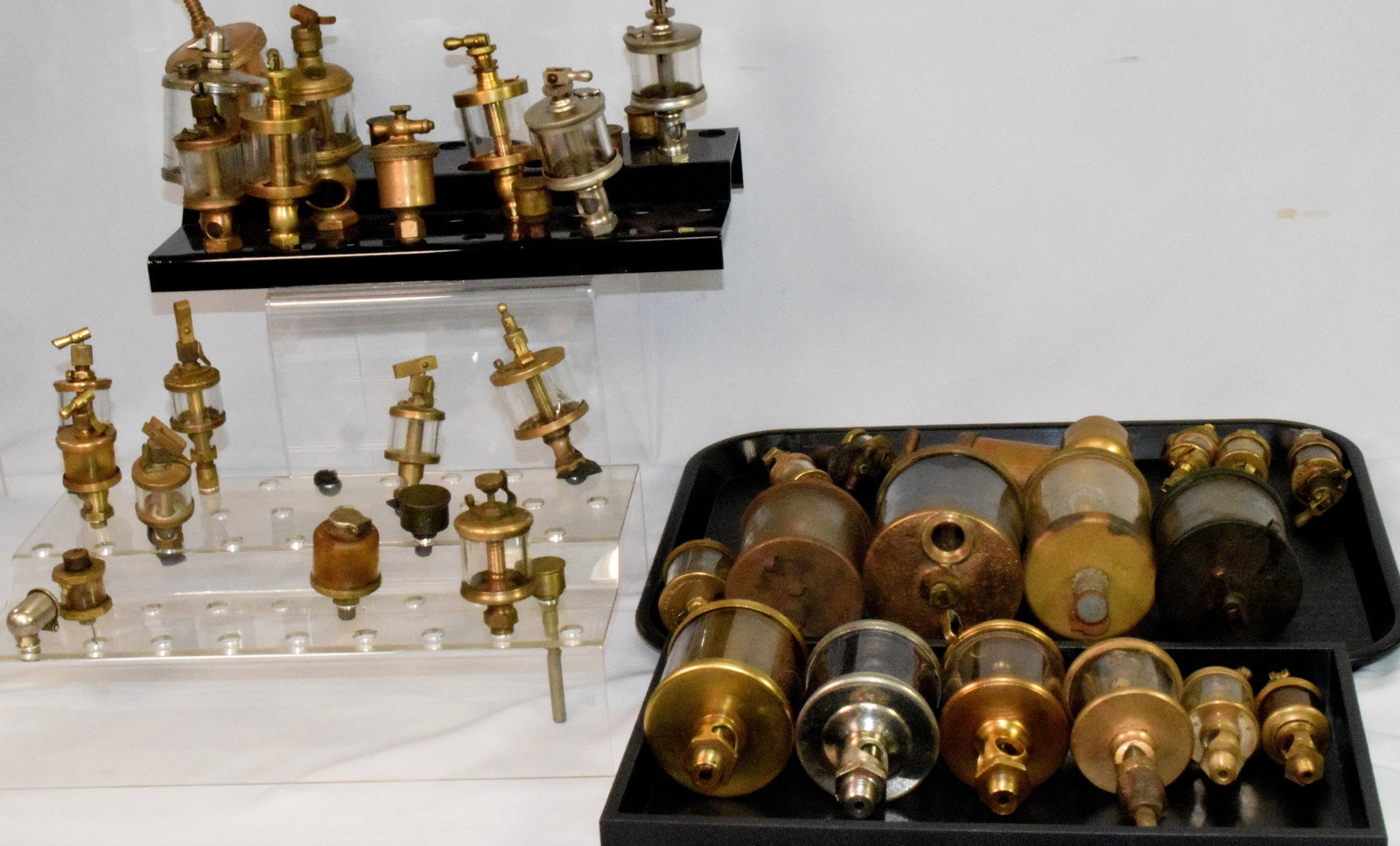 LARGE COLLECTION OF BRASS ENGINE DRIP OILERS: Consists of various sizes and makers. Some of the company names are Lunkenheimer, Penberthy Injector Co, Sherwood, and etc. Total ot 37 pieces plus caps or attachments. Three have damage to glass.Some