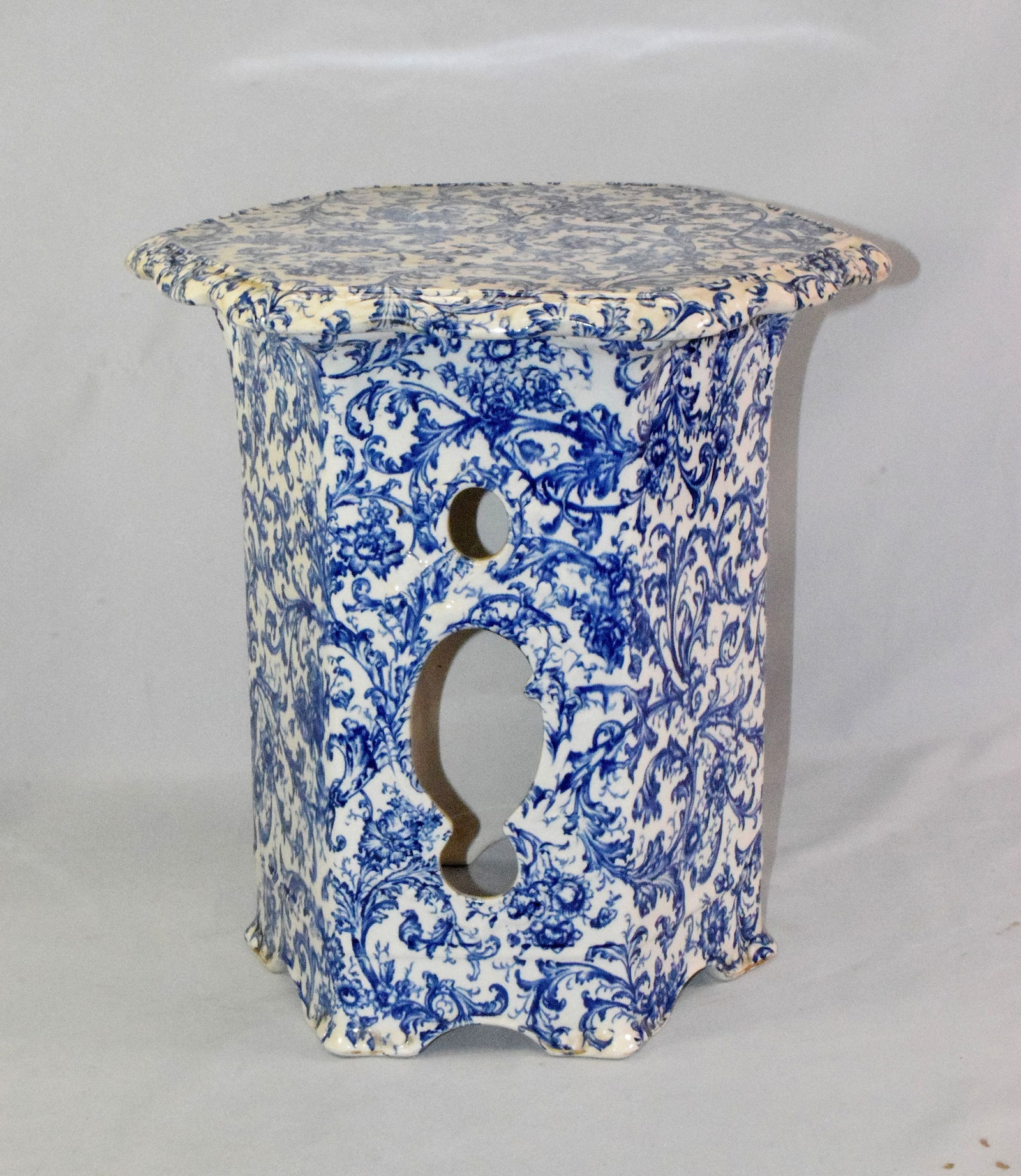 FLOW BLUE GARDEN SEAT BY MADDOCK WORKS: Flow blue six sided garden seat with lobbed rim and overall floral decoration,by Maddock Works. Some wear, old hairline crack on top and discoloration. Measures approx. 15 inches tall.Weighs approx. 2