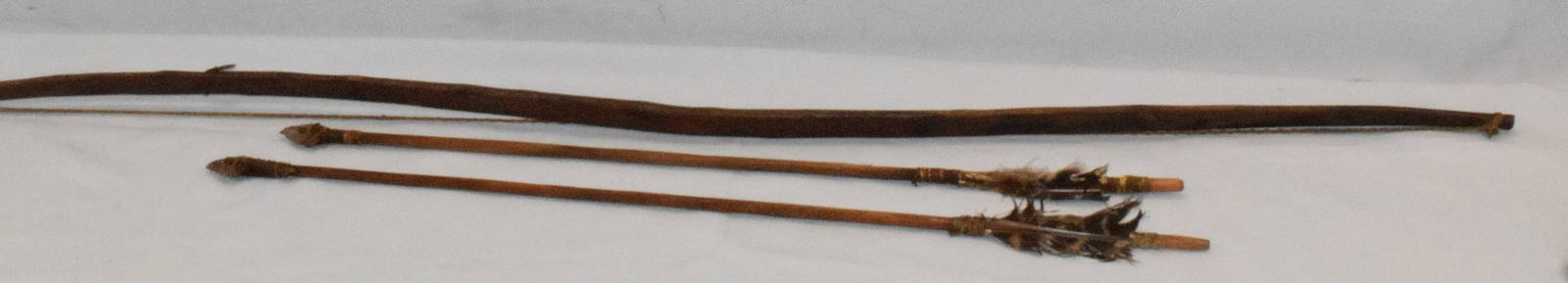 19th NATIVE AMERICAN WOODEN ARROWS & BOW: Plains Indian. Consists of wooden bow & arrows. Brass tag numbered #21 Bow & arrows. 45 inches long. Original patina and color. Sinew for strings. Two with attached stone original tips with senew stri