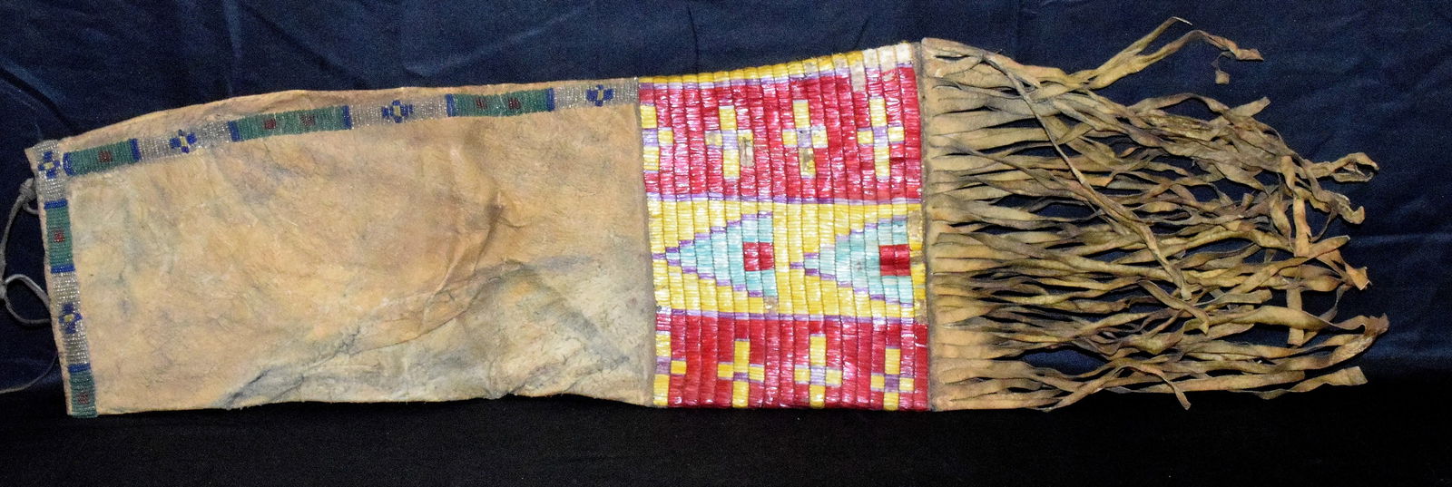19th PLAINS INDIAN BEADED & QUILL WORK HIDE PIPE BAG: Ca late 19th-1910. Plains Beaded Pipe Bag with Geometric Design and Quill Work 29" L. Including Fringe 8" W. Some damage or loss on quill work. We Believe it is some insect damage. Hide dry and stiff.