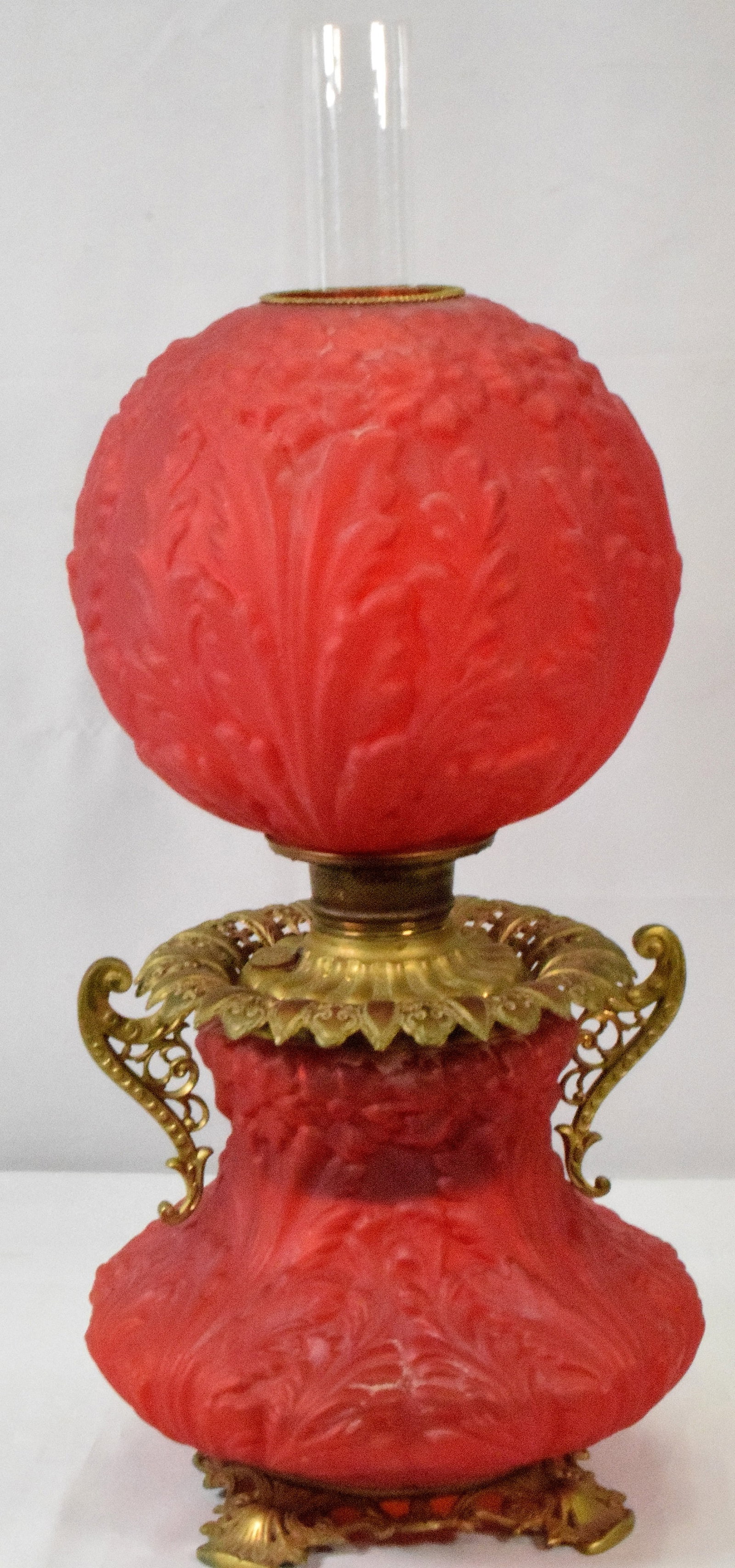 19TH GONE WITH WIND RED SATIN GLASS OIL LAMP: 19th Victorian Gone with the wind red glass oil lamp. Double handled. Brass trim foot. Embossed ball shade and base. Base and top are a perfectmatch. Ca 1880's-1890's. 27 inches to top of chimney x 12