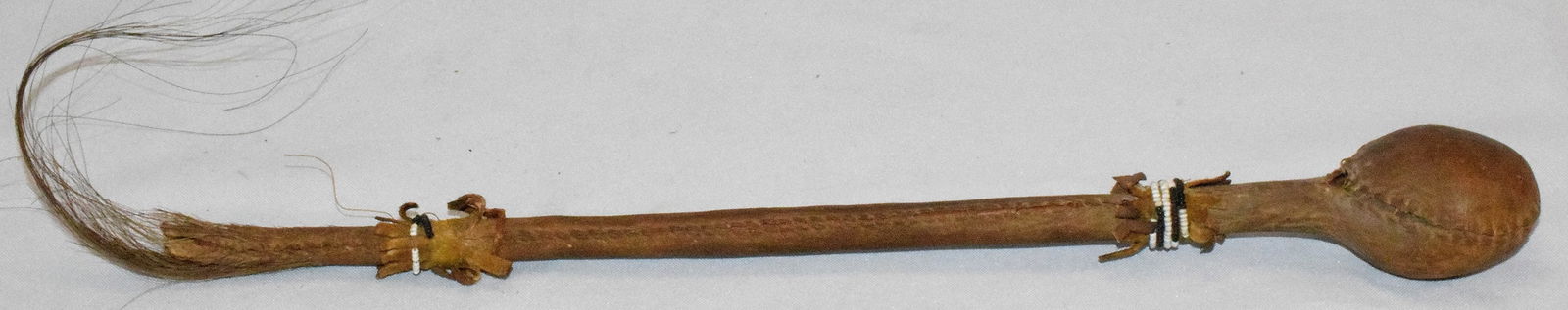 19TH PLAINS NATIVE AMERICAN SLUNG-SHOT CLUB: Hide Floppy slung-shot skull cracker war club. Staff hide covered. Some beaded accents. Horse hair end. Some stitching separation. Original untouched condition. 14 inches long.