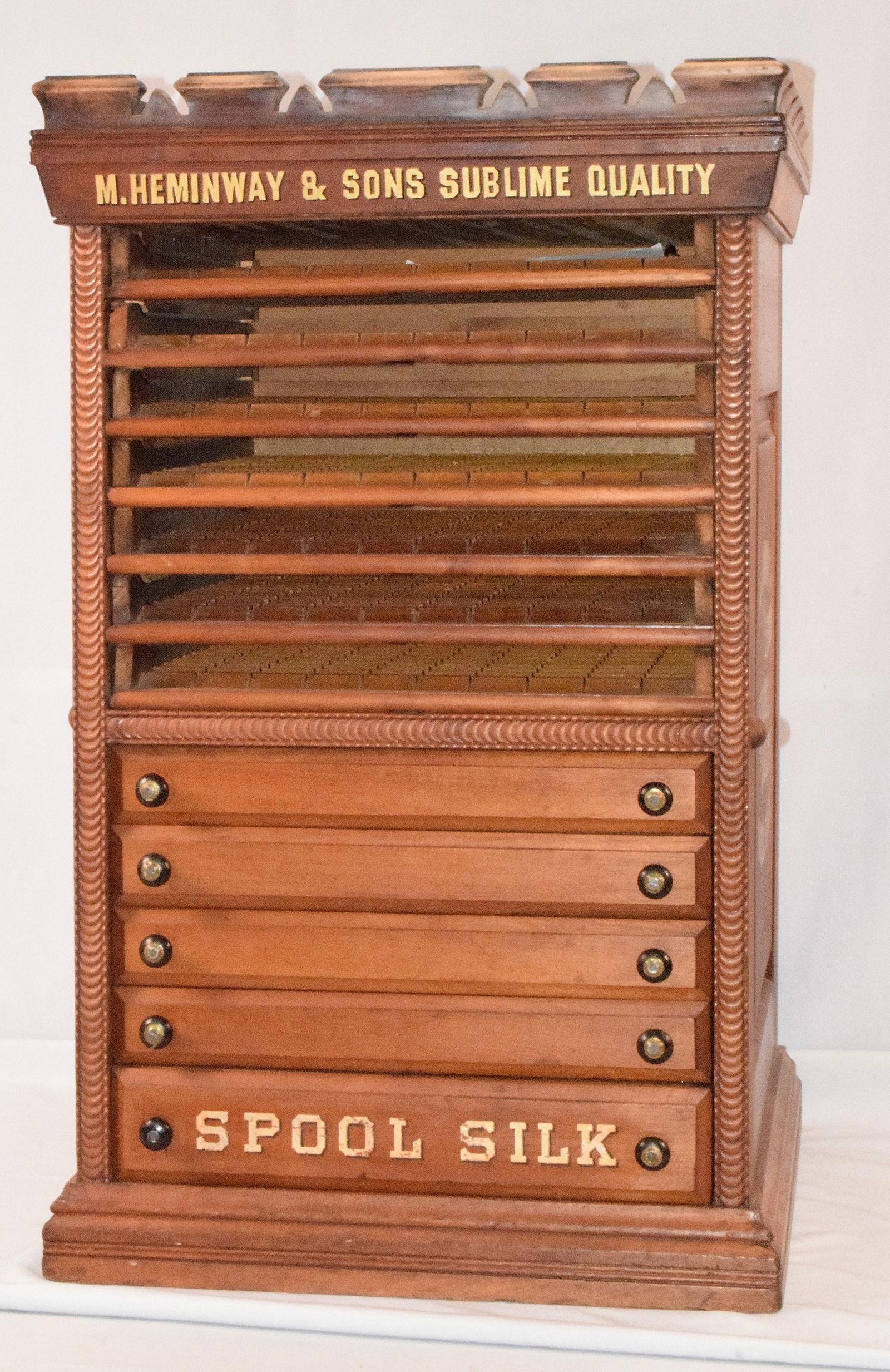 ANTIQUE M. HEMINWAY & SONS SPOOL CABINET: 19th century Victorian mahogany silk spool advertising cabinet. for M. Heminway & Sons Sublime Quality Spool Silk. Raised panels sides, carved gallery top, rope design detail. Seven slide out glass sh