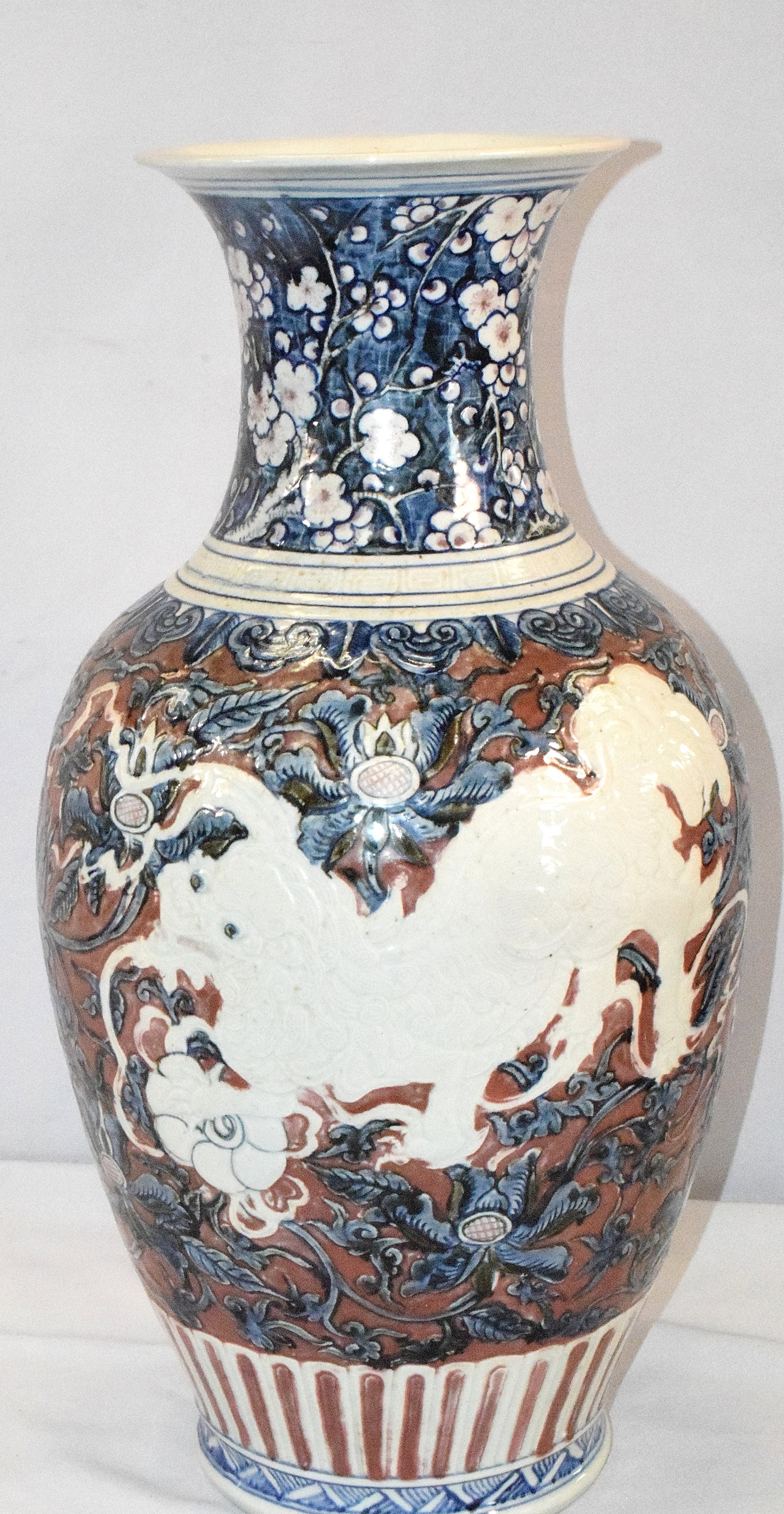LARGE CHINESE PORCELAIN FOO DOG VASE: Large Porcelain vase. Chinese. 20th century. Baluster form. Carved decoration of Foo dogs, Stylized floral scrolling. Under-glaze blue and red decoration. Good condition. 24 inches tall.