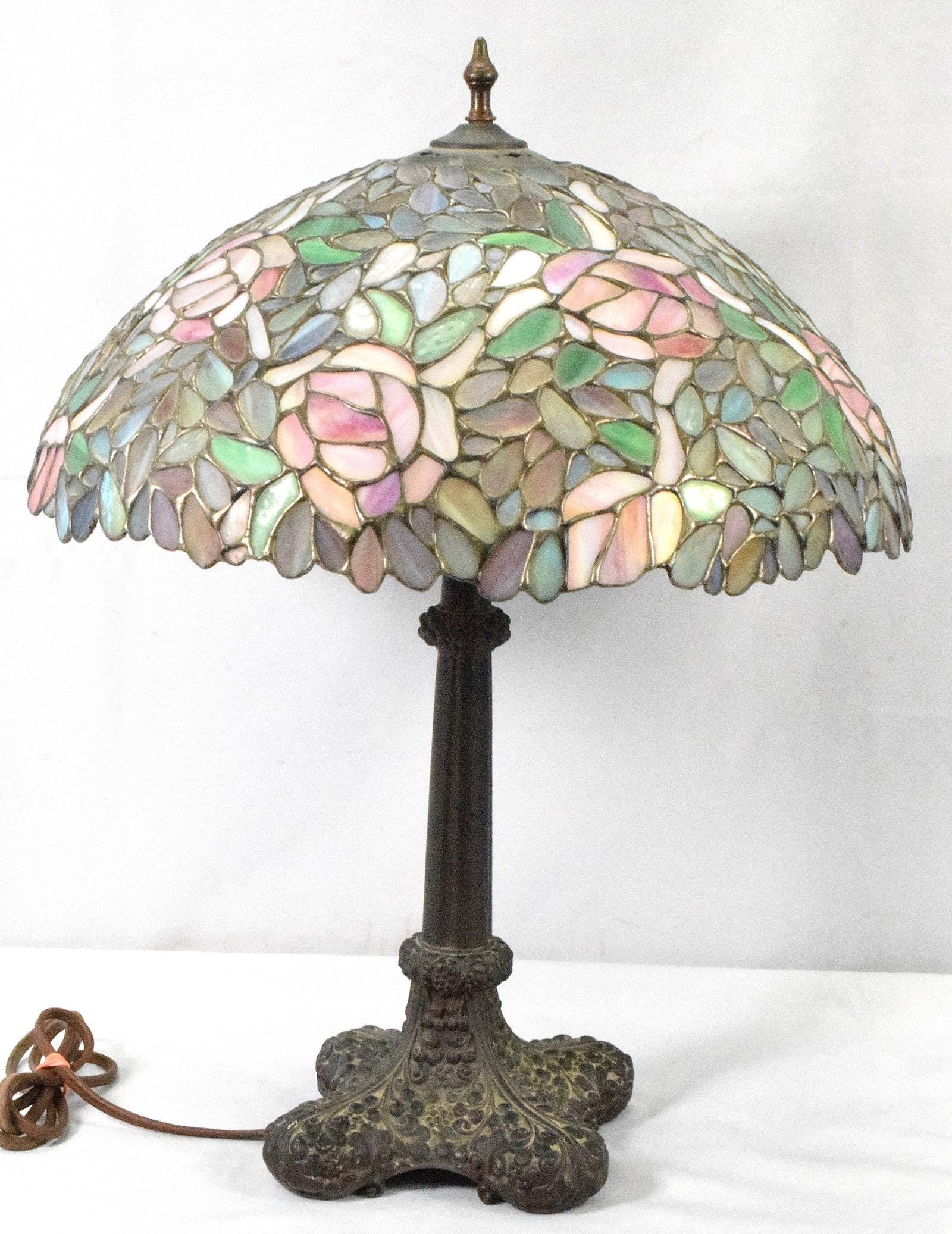 LEADED GLASS TABLE LAMP: Leaded glass table lamp. 24 inches tall with 18 inch shade. Shade with floral design. Heavy metal patina base. No marking. Age not known. Estate lamp. Working condition. Shipping weight Good condition