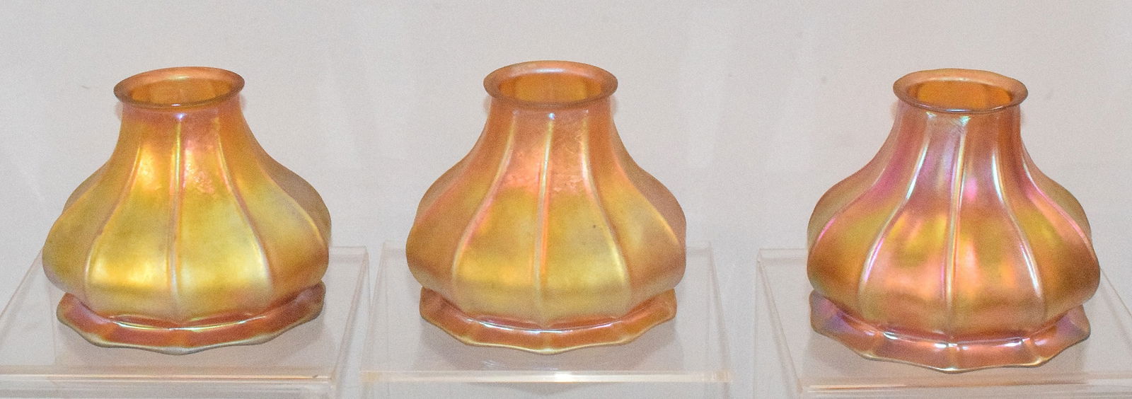 (3) STUEBAN SIGNED GOLD AURENE ART GLASS SHADES: Wonderful set of three gold iridescent aurene ribbed art glass Stueben hanging lamp shades. Two of the three have the Steuben mark on rims. Visible in photo Bell shape lamp shades. 2 inchtops x 4 1/2