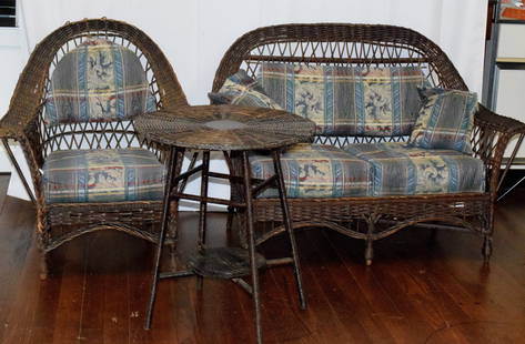 THREE PIECE PORCH WICKER SET: Consists of settee, arm chair and side table. Not painted. Original finish. Some breaks and loss. Original drop seats. Ca 1920's or 1930's.