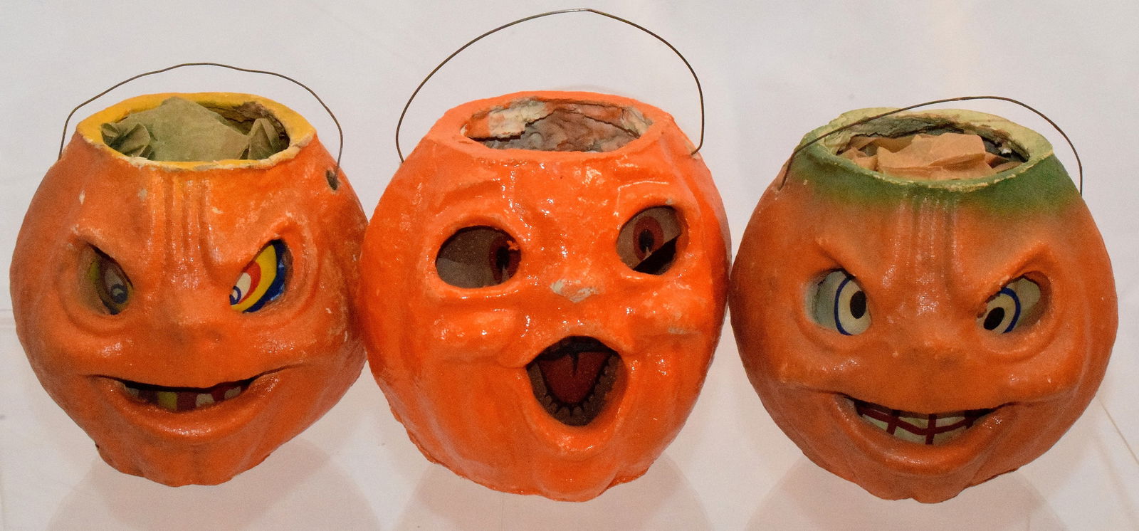 PULP PAPER MACHE HALLOWEEN PUMPKIN JACK O LANTERNS: Grouping of three vintage Pulp Paper Mache Halloween Pumpkin. Bailed wire handles. One double sided. Some wear. The double sided one has loose eye piece and the other side with loss to one eye. The tw