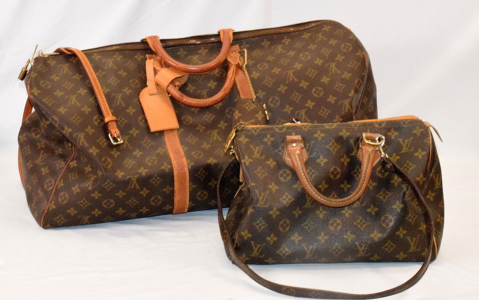 2 LOUIS VUITTON ASSEMBLED ITEMS: 1) A brown and tan Monogram coated canvas Louis Vuitton Keep all. brass hardware, dual rolled top handles and Vachetta leather trim. Canvas lining with zip closure at top. Includes luggage tag andhand