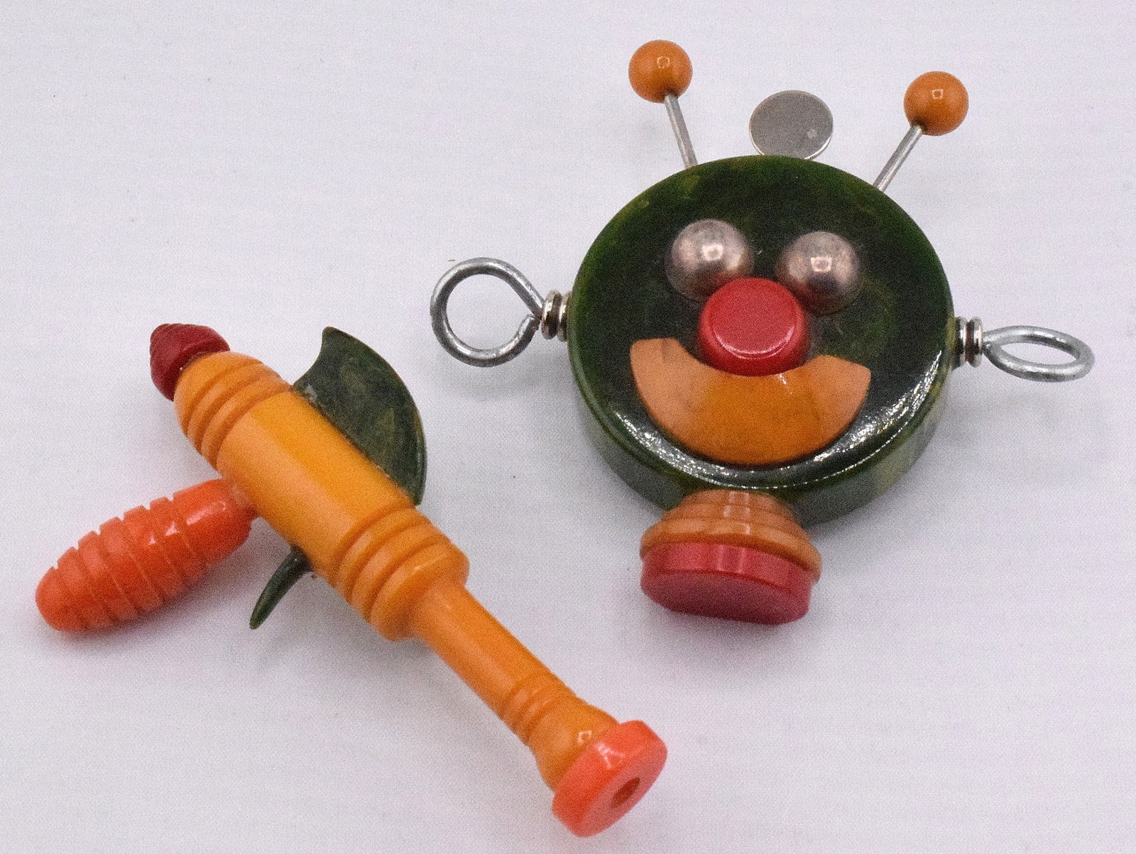 2 MCM BAKELITE SPACE PINS.: Set of 2 Colorful MCM Bakelite space Pins Brooches. Ray gun and spaceman or robot. Both in good condition. Spaceman approx. 3 inches diameter.