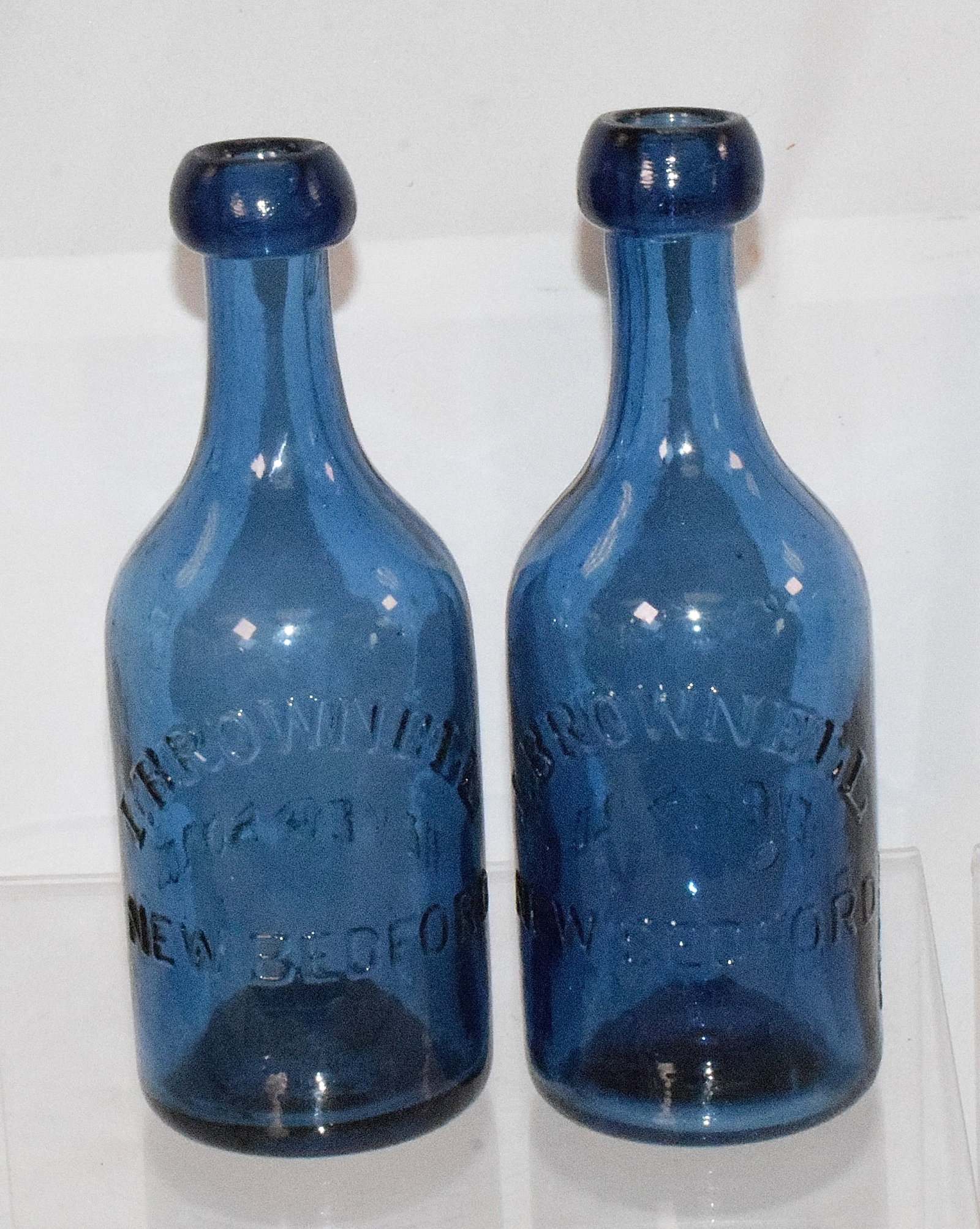 19 ASSEMBLED NEW BEDFORD GLASS BOTTLES: Consists of 1) Glass milk bottle with lid. Marked etched New Bedford. 2) Milk bottle No lid. Etched New Bedford. 3) Eagle Nedbedford with cap Aqua. 4) Dr Sweets New Befford Aqua. 5) W A Pease NewBedfo