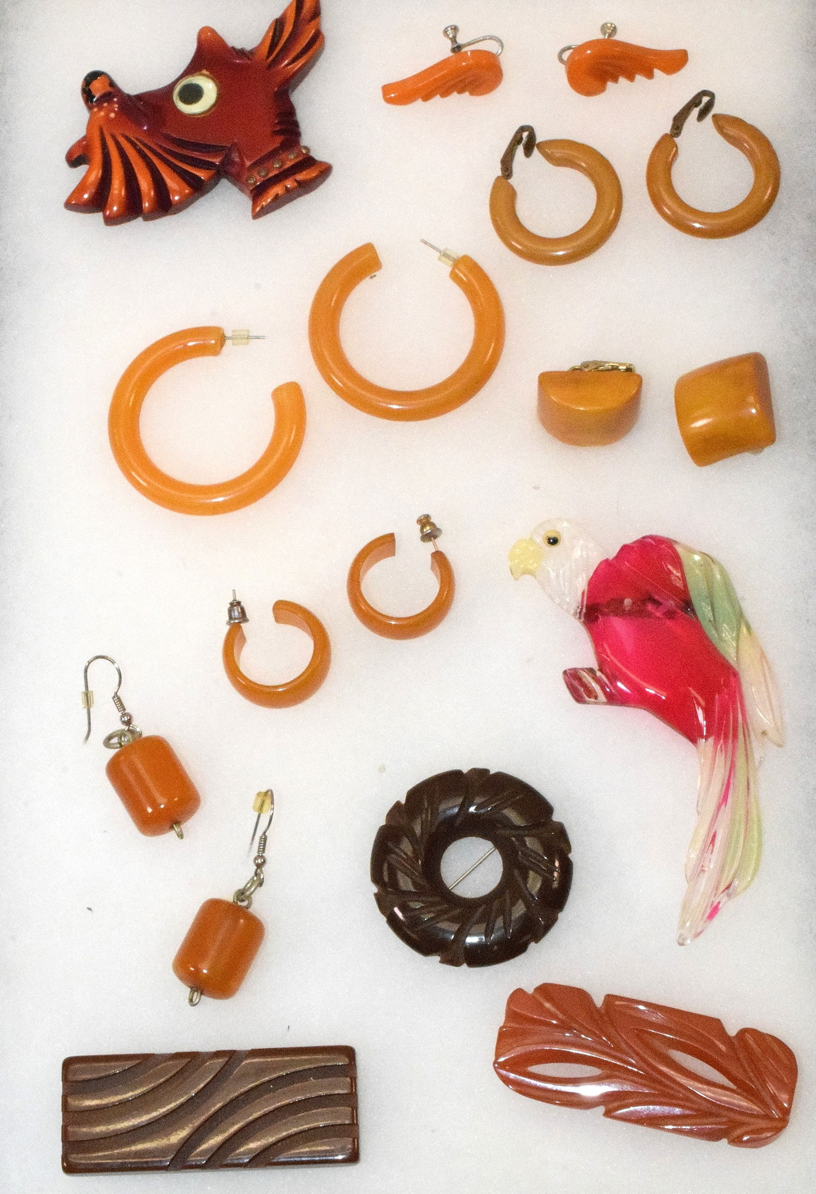 ART DECO BAKELITE JEWELRY GROUPING: Grouping of bakelite jewelry. 1) Scotty dog brooch. 2) 3 Art Deco pins. 3) 3 pairs of pierced earrings. 4) 3 pairs of clip earrings. 5) Lucite parrot brooch.Grouping in good condition, some expected w