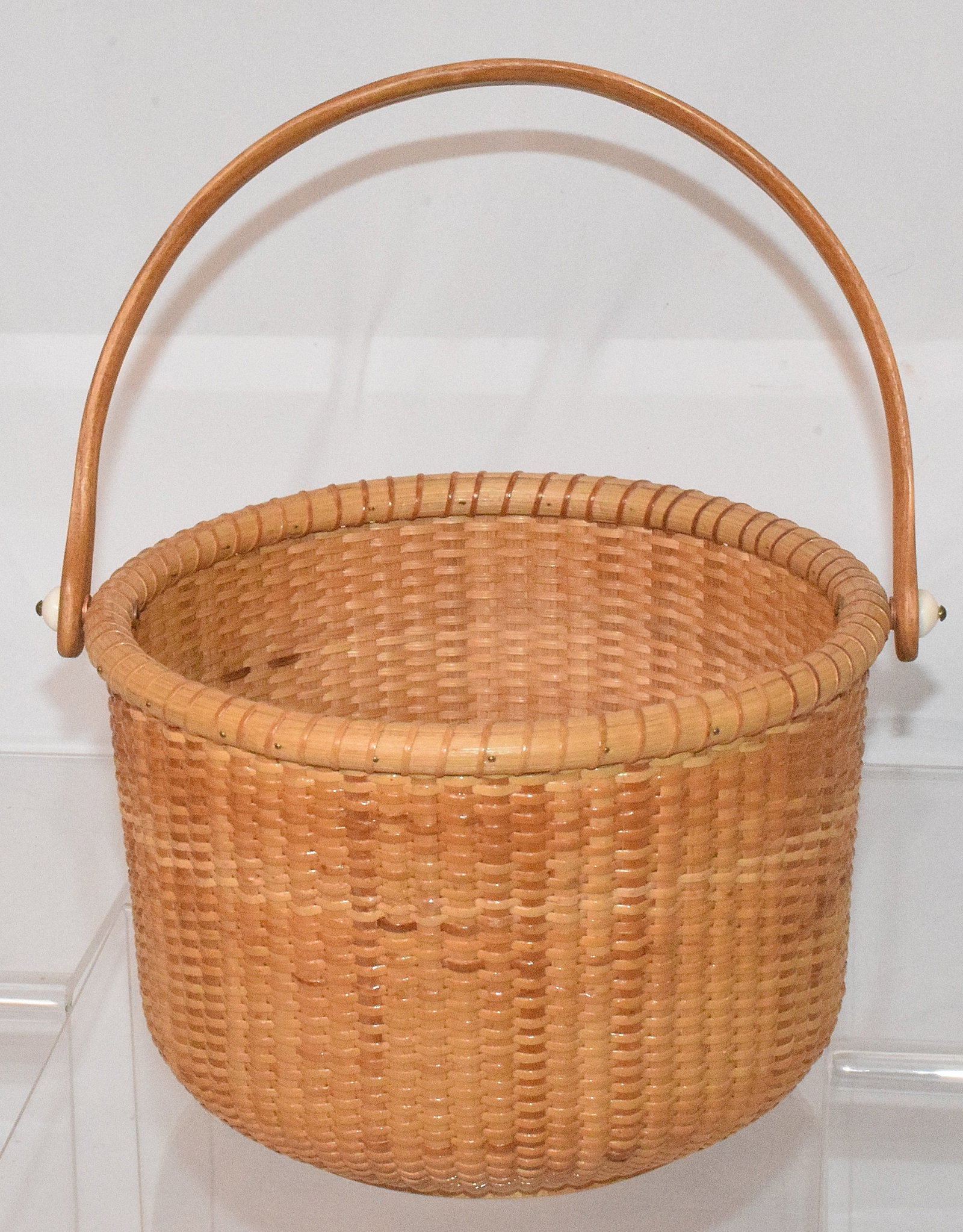 20TH NANTUCKET LIGHTSHIP BASKET: 19th century, Nantucket lightship swing handle basket, signed "NLB 1990" on bottom of basket. Good condition. Diameter: 7in, H: 5in.