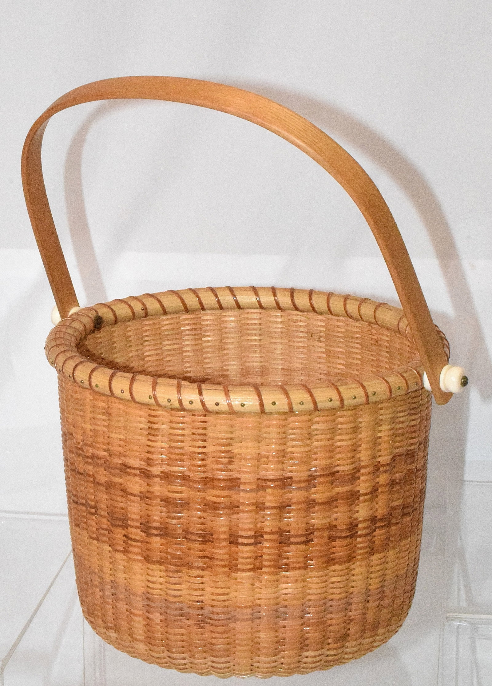 20TH NANTUCKET LIGHTSHIP BASKET: 20th century. Nantucket lightship swing handle basket, signed "NLB 1990" on bottom of basket. Good condition. Diameter: 7in, H: 6in.