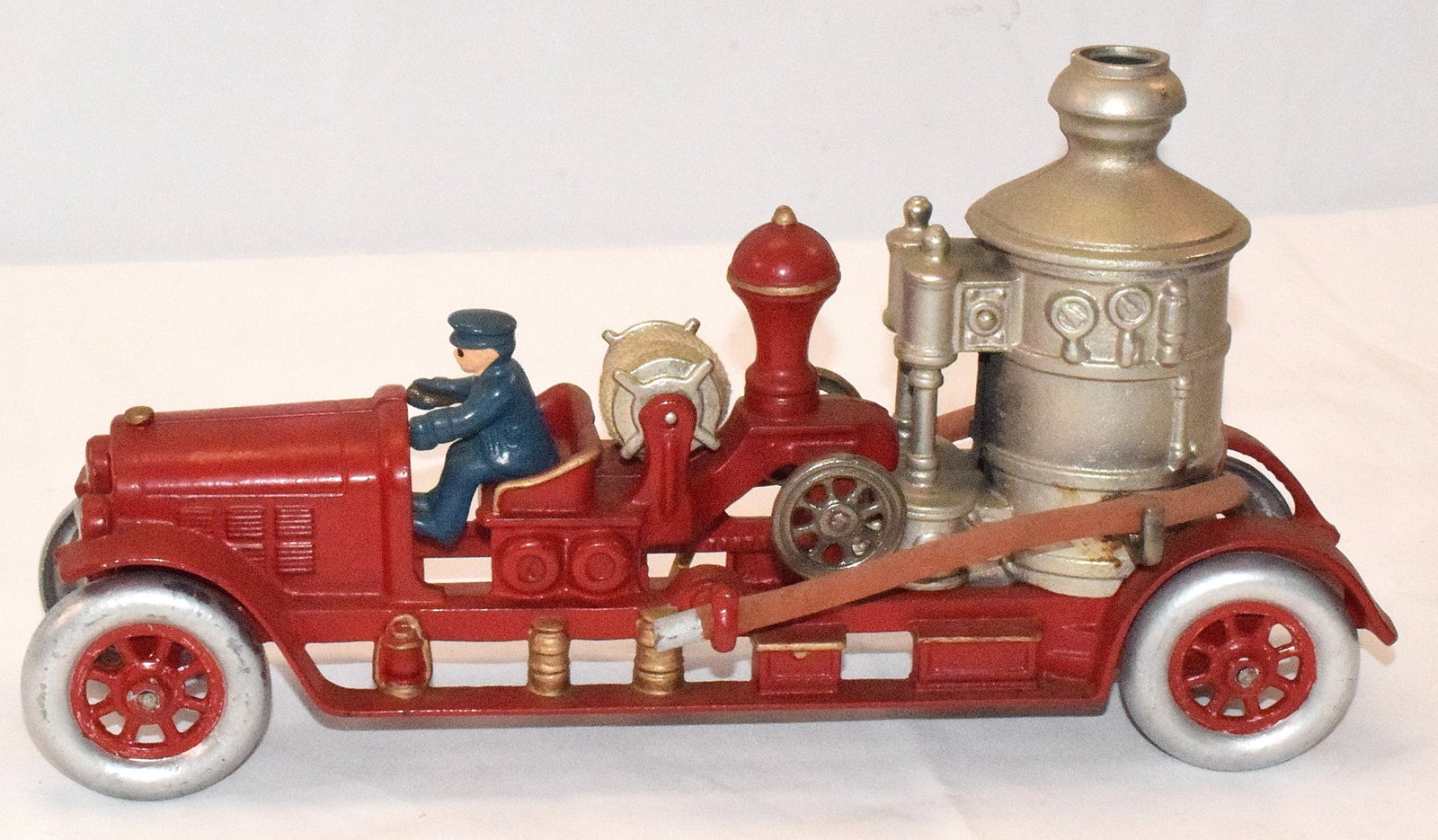 CAST IRON FIRE PUMPER TRUCK: Kenton toys red fire pumper truck, cast iron, original front rider, missing rider on back. Wheels have been repainted, original hose with rubber hoses attached to tank in back. Goodcondition. L: 14 1/