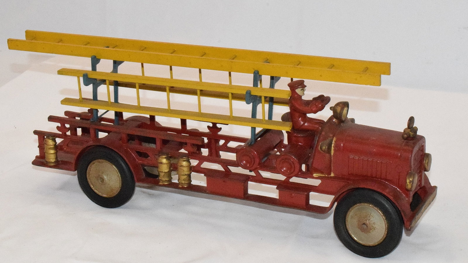 HUBLEY CAST IRON TOY LADDER TRUCK: Red ladder truck from hubley, cast iron, missing rider in back, original rider in front. Gold trimmed parts and rider have been repainted. All parts are functional. Good condition. L: 18 1/2in, W: 3 1