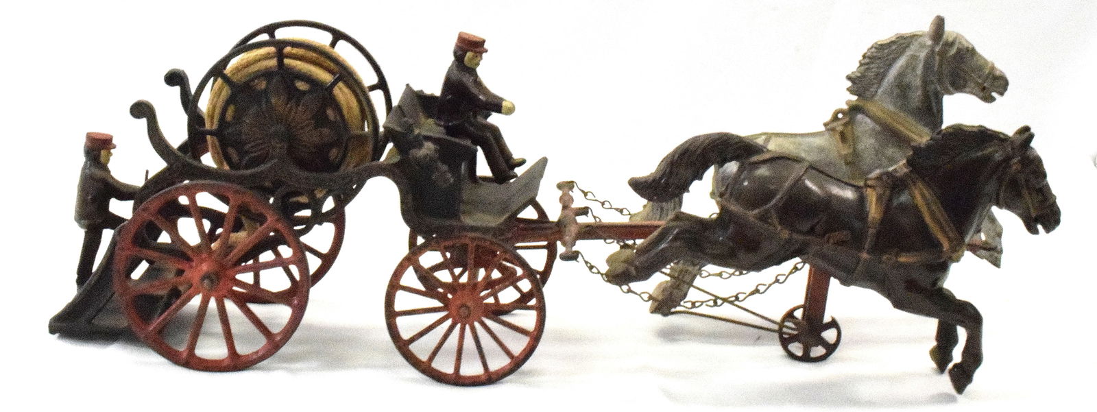 CAST IRON HOSE REEL TOY WAGON: Cast iron wagon, horse drawn with original horses, 4 wheels in back one in front. Original paint, has both original riders, hose is original, wheel in front has a break in it. Good condition. L:25in,
