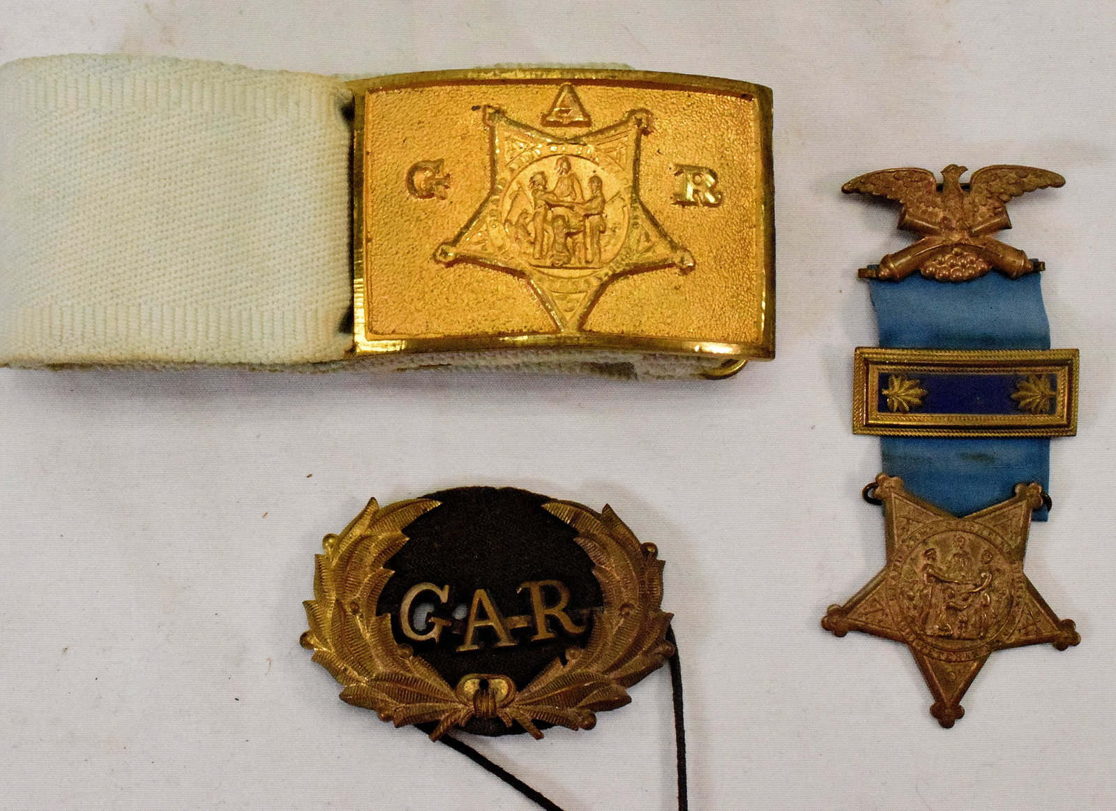 (3) GRAND ARMY OF REPUBLIC OR GAR GROUPING: Ca post US Civil War. Consists of 1) GAR buckle and belt. Original condition. Buckle 2 3/4 x 1 3/4 inches. Original belt. 2) GAR Kepi badge. Some moth damage. 3) Grand Army of the Republic (GAR)Member