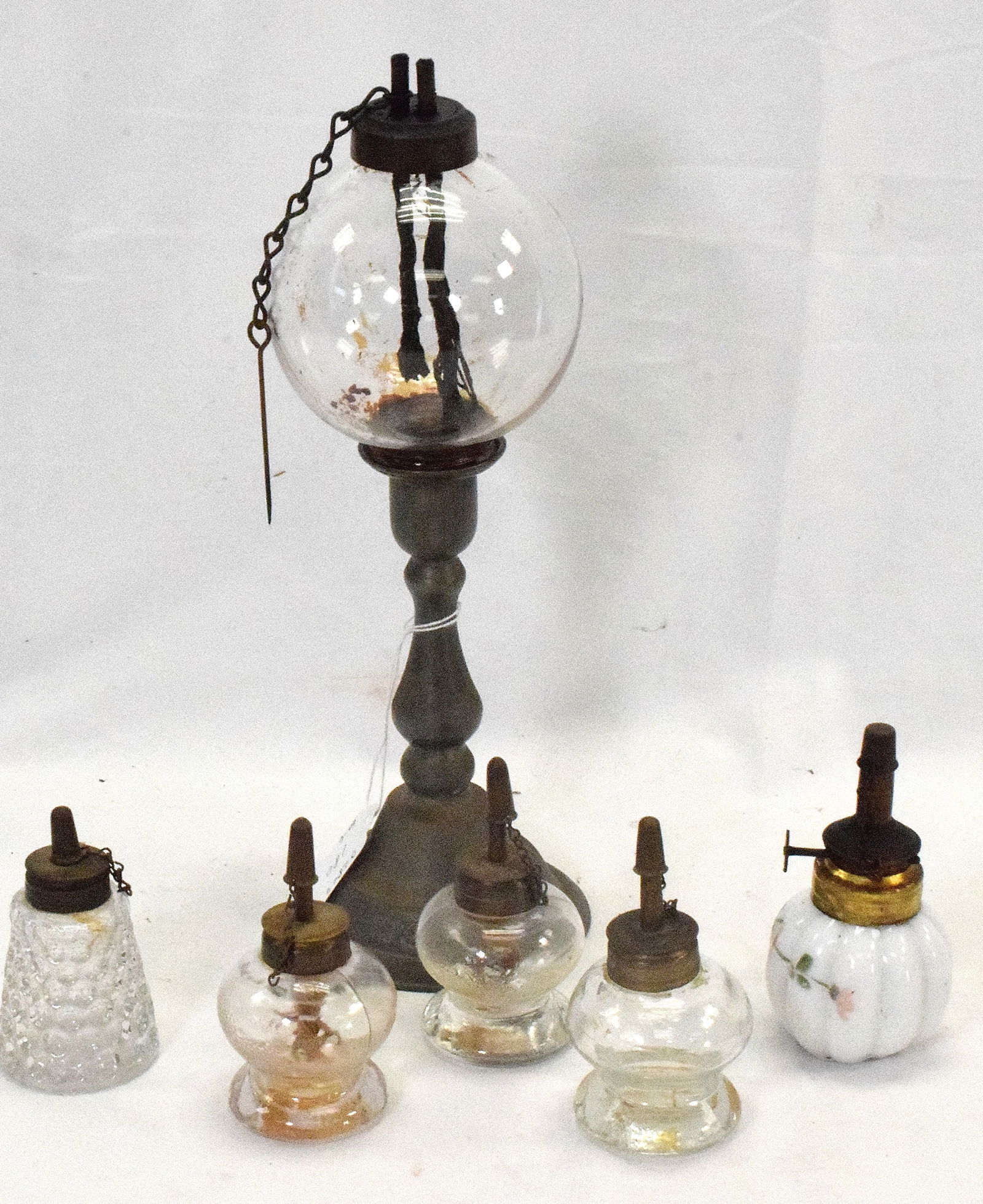 19TH NEW ENGLAND WHALING LAMPS: Consists of 6 lamps. All with original burners. Four are glass possibly Sandwich glass. One white glass with hand painted floral decoration.. Possibly New Bedford. Ball clear shade pegged lamp font wi