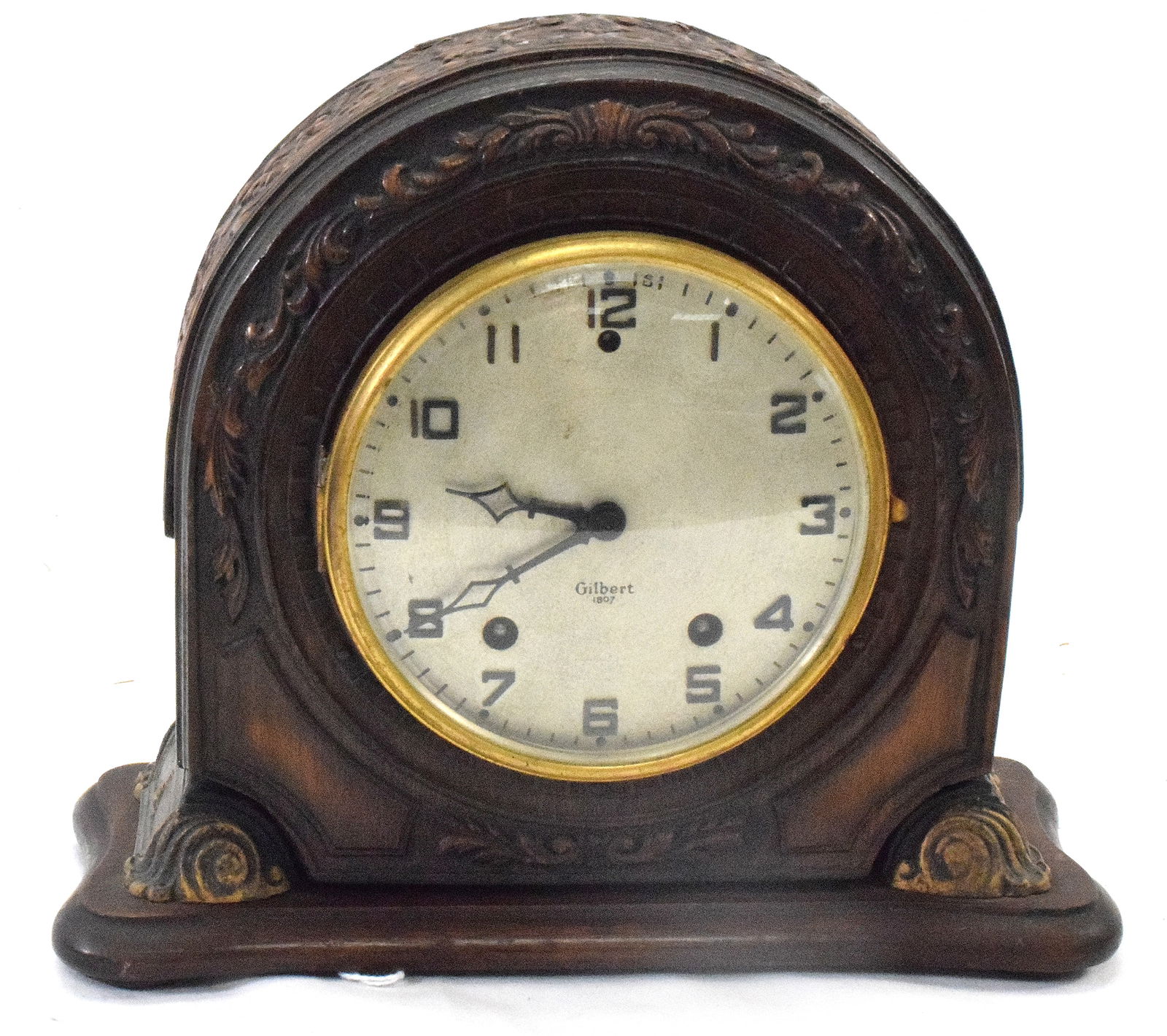 GILBERT CARVED MANTLE CLOCK: Detailed Mahogany carved Gilbert mantel clock. Gilt gold accents. 8 1/2 inches tall x 9 1/2 inches wide. Fancy carvings. Missing pendulum. Works are complete. Do not if working. As is.