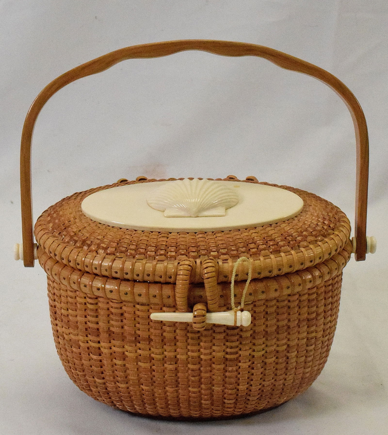 GERALD L BROWN NANTUCKET BASKET PURSE: Nantucket, Massachusetts, Contemporary Oval, with shaped swing handle. Plaque with carved shell mounted to lid. Inside bone plaque marked "Kathy" flank with flowers. Inside basket purse signed G L Bro