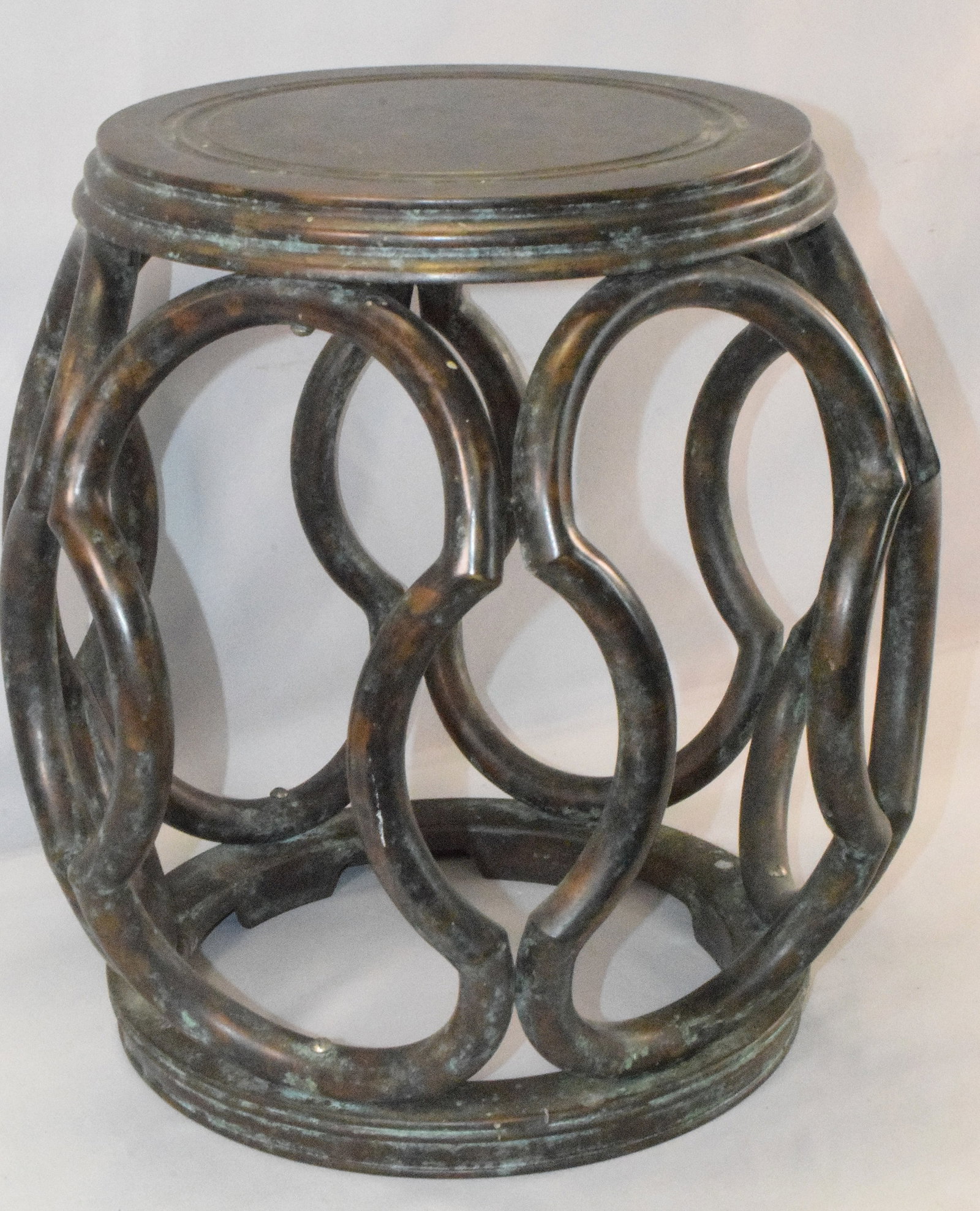 BRONZE GARDEN SEAT: Bronze garden seat with interlocking oval supports. 18 inches tall x 21 inches diameter. Original patina. Ca 1920's. The Estate of Nicholas Mitropoulos 1952-2025