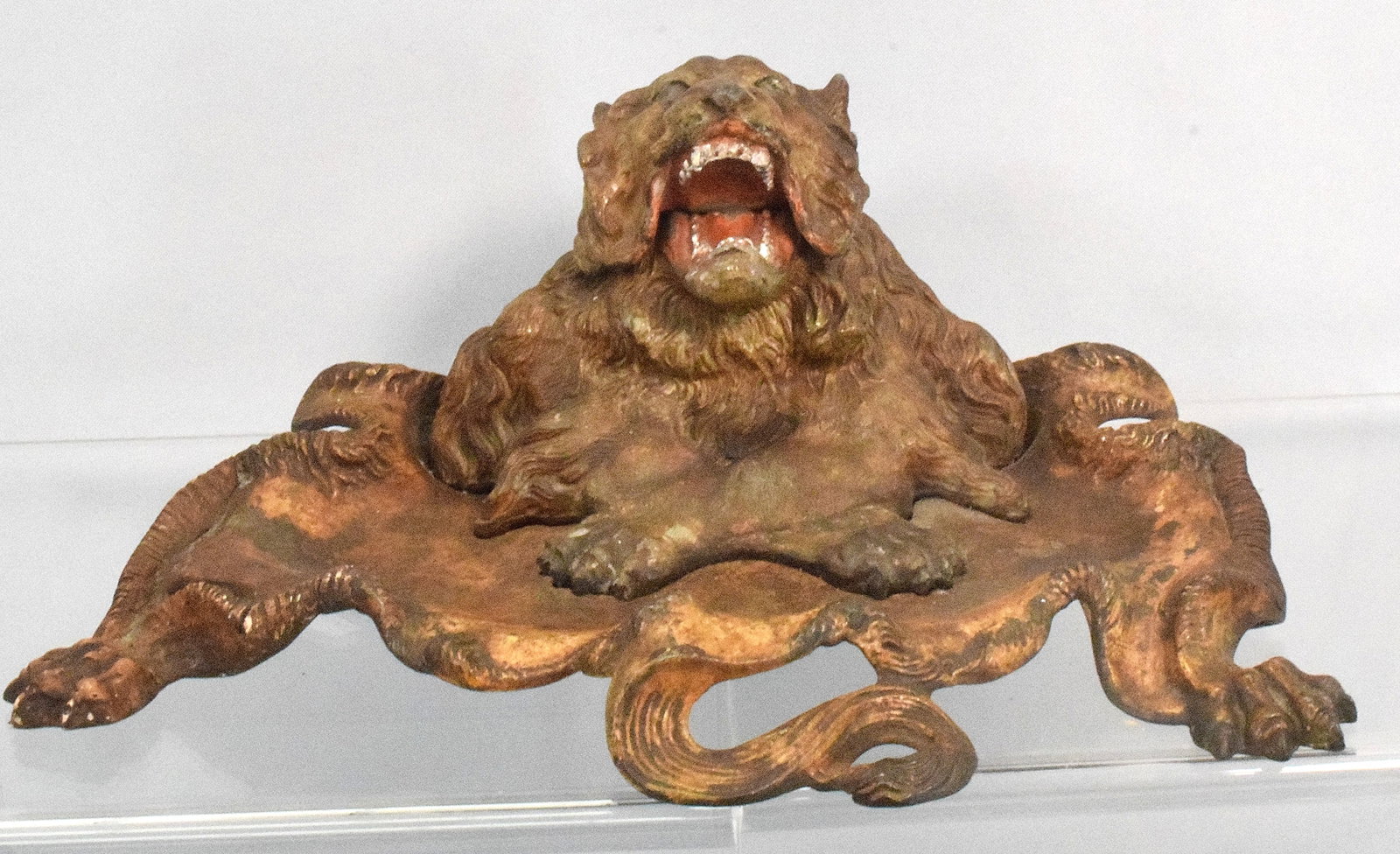 CAST IRON ROARING LION INKWELL: Ca 19th century. Cold painted cast iron inkwell. 4 3/4 inches tall x 12 1/2 inches wide. Wear to paint. Paint is original. Heads lifts up. Has a glass liner. The Estate of Nicholas Mitopoulos1952-2025