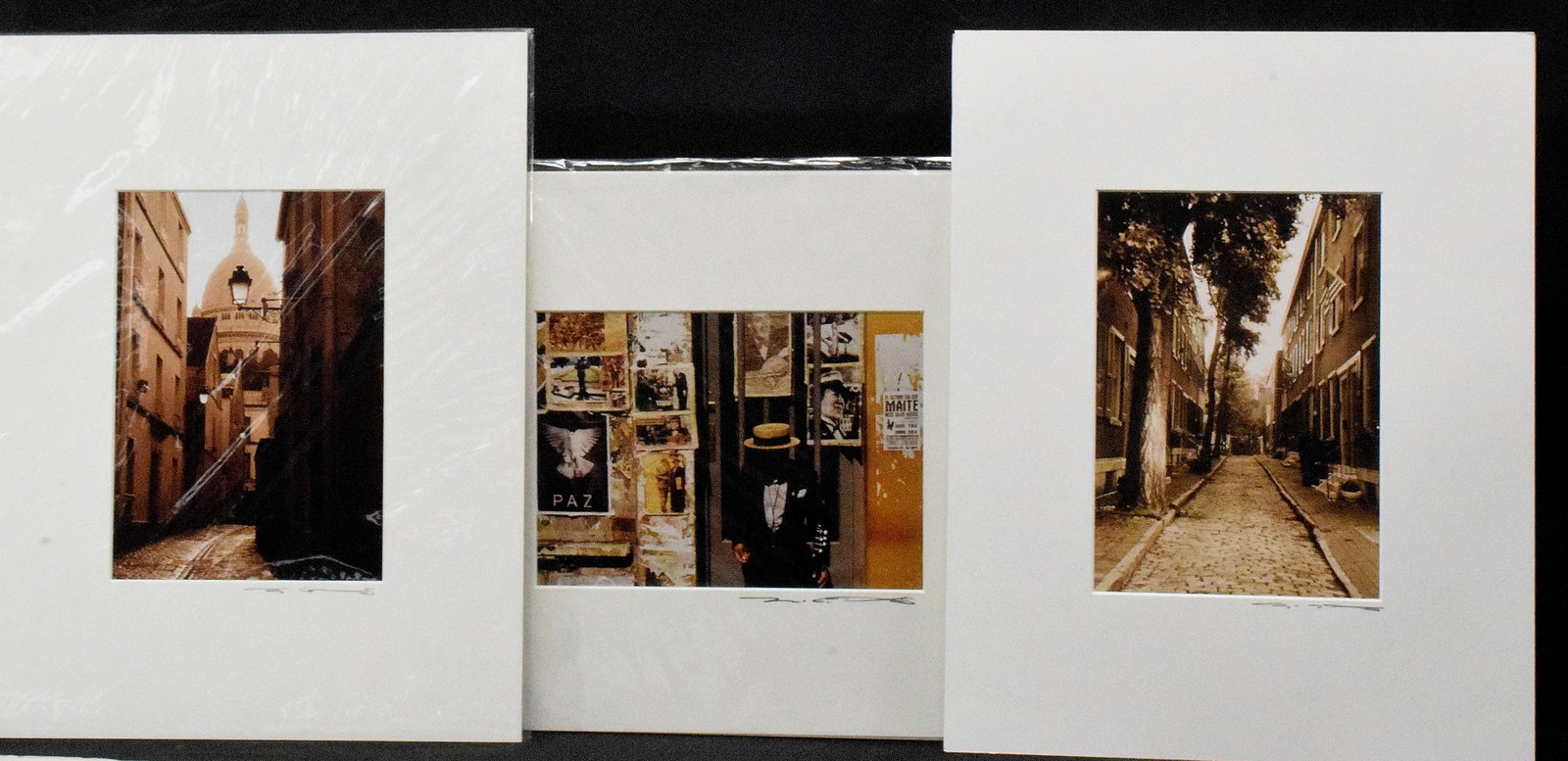 (3) SEPIA-TONE SIGNED PHOTOGRAPHS: Signed signed in pencil. 1) Depicts historic cobblestone street with row houses and American flags. 2) Montmartre Street in Paris. 3) Figure in front of layered vintage poster and doorway.Artist not k