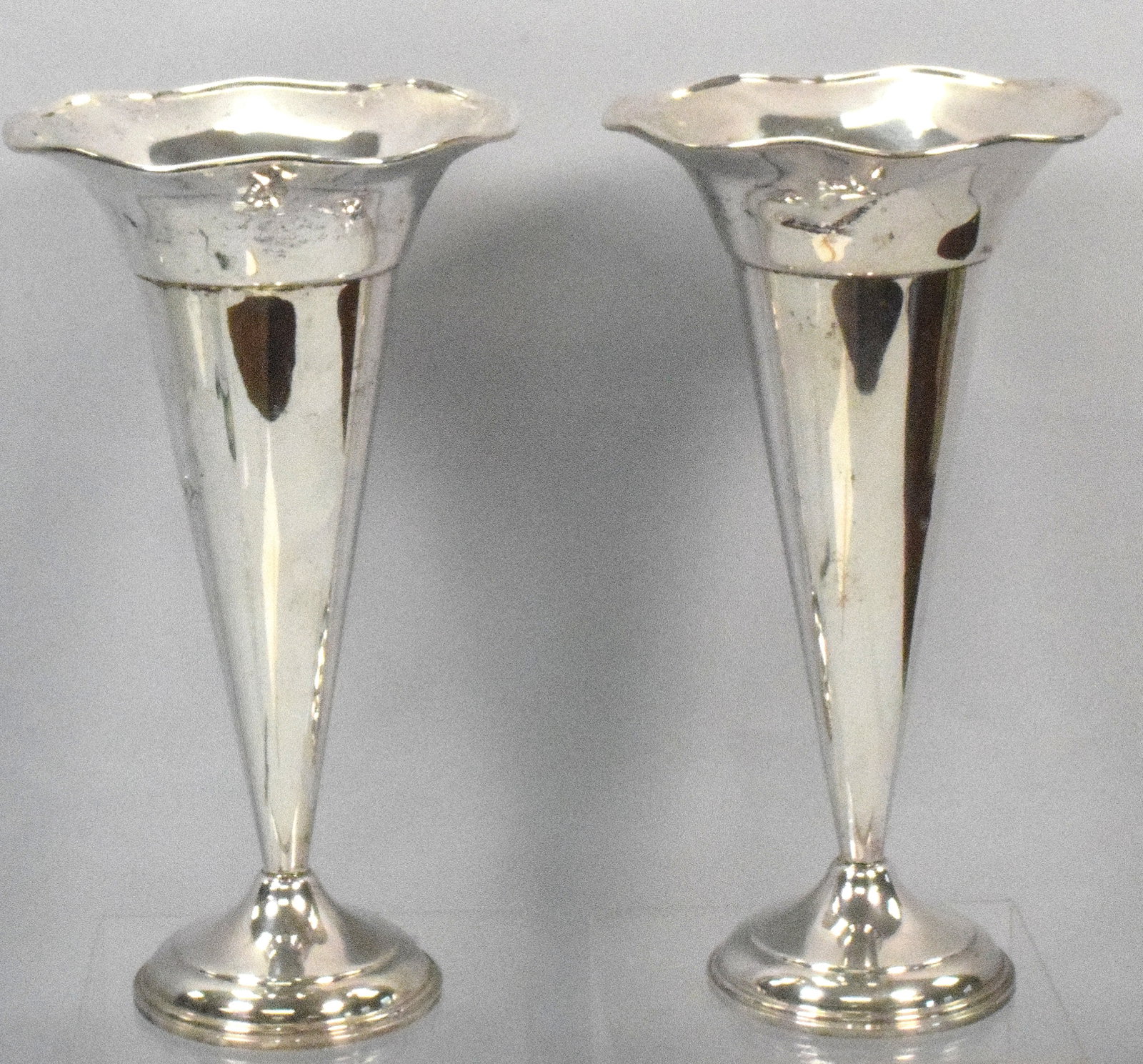 PAIR OF STERLING SILVER TRUMPET VASES: Sterling silver flare top trumpet vases. Ca 20th century. Weighted bases. Vases 11 3/4 inches tall flare 6 1/2 approx diameter. Monogrammed. Some dents. The Estate of Nicholas Mitropoulos1952-2025.