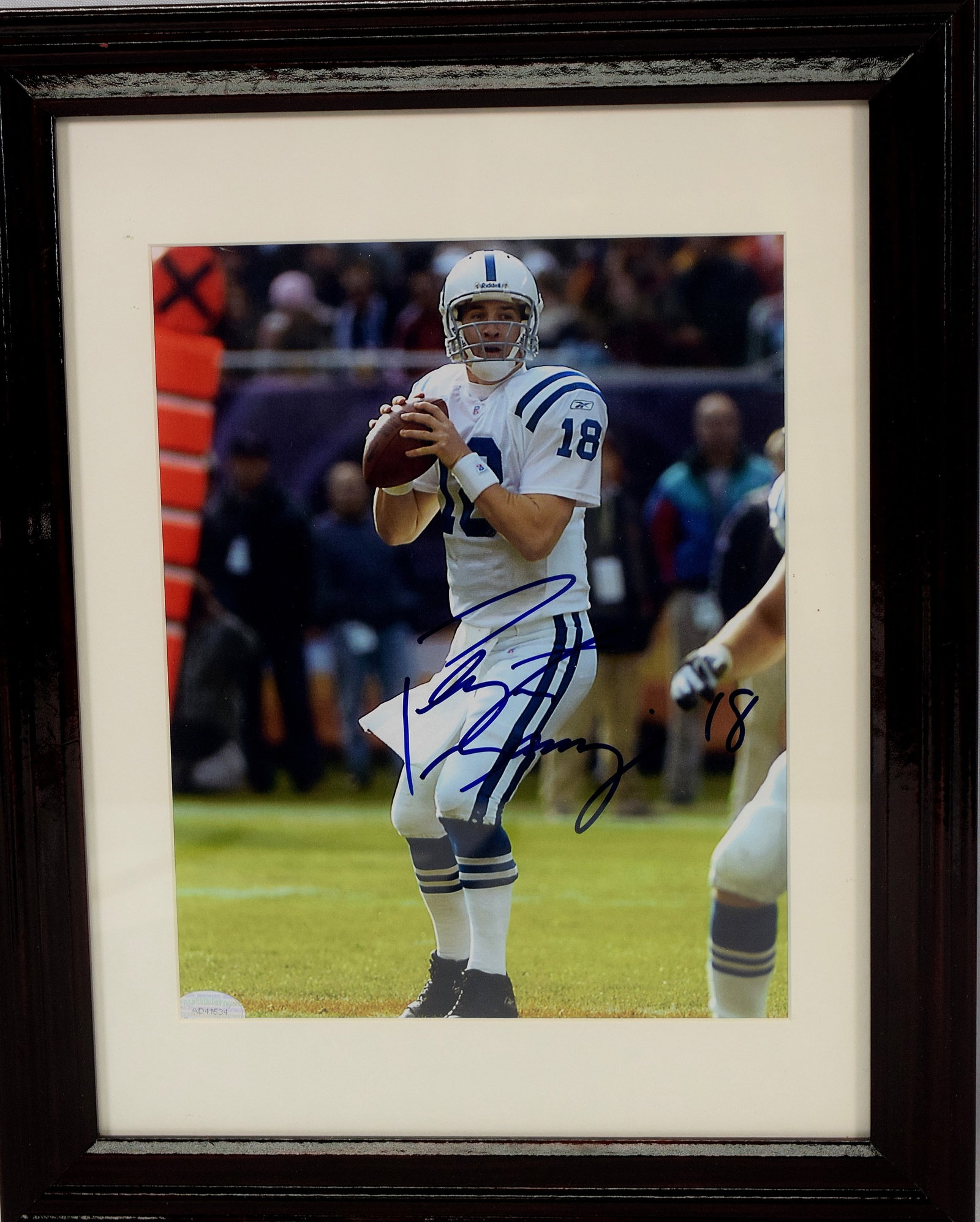 FRAMED AUTOGRAPH PEYTON MANNING PHOTOGRAPH: Signed in blue ink on photo with Peyton Mannings number 18 which he had when he played with the Colts. Certificate of authenticity taped on the backside. Good condition. Frame 15" x 12", photo:8" x