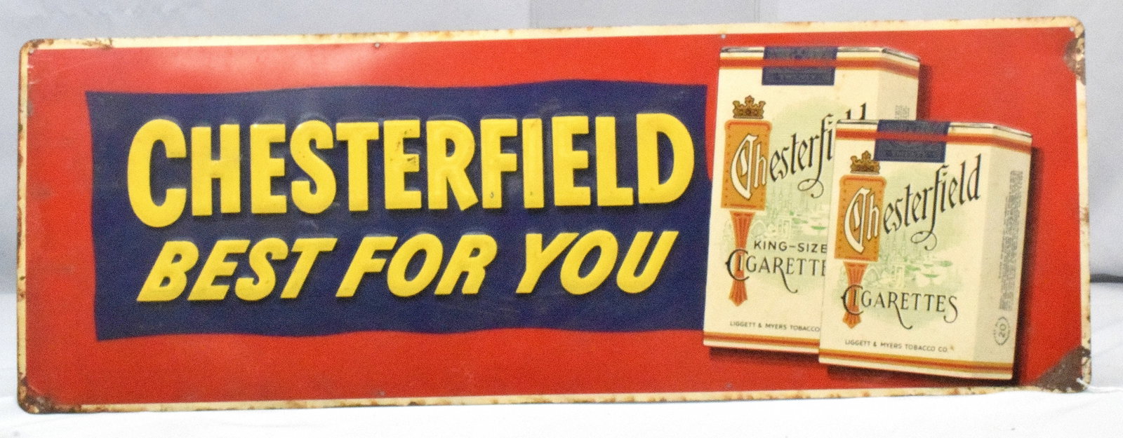CHESTERFIELD CIGARETTE METAL SIGN: Advertising sign for Chesterfield Cigarettes. Horizontal, red background with yellow text "Best For You" set on blue background. Some rust and paint loss around edges. Good condition. 12in" x34in",